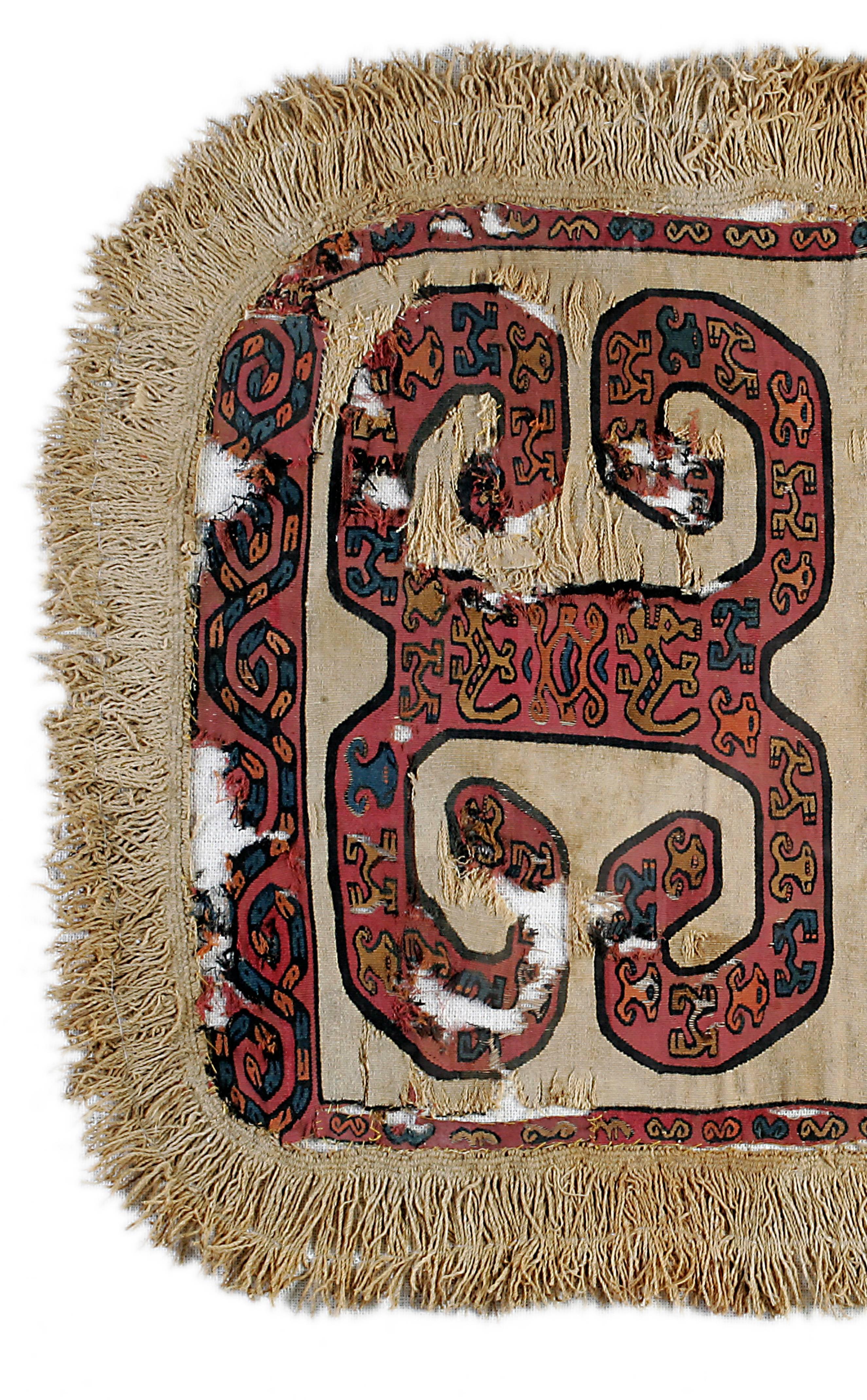 Panneau rectangulaire semi-ovoïde à bordure fortement frangée présentant un motif géométrique multicolore très étroitement tissé, composé de deux rinceaux contenant de multiples zoomorphes stylisés. Serpent entrelacé dans la bordure inférieure.