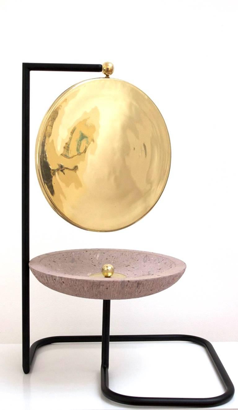The duality of whim and methodical design meets in the Satelite vanity mirror by Nomade Atelier contemporary Mexican design. Its spinning face shows brass on one side and mirror on the other. Its pink quarry stone bowl is the perfect receptacle for