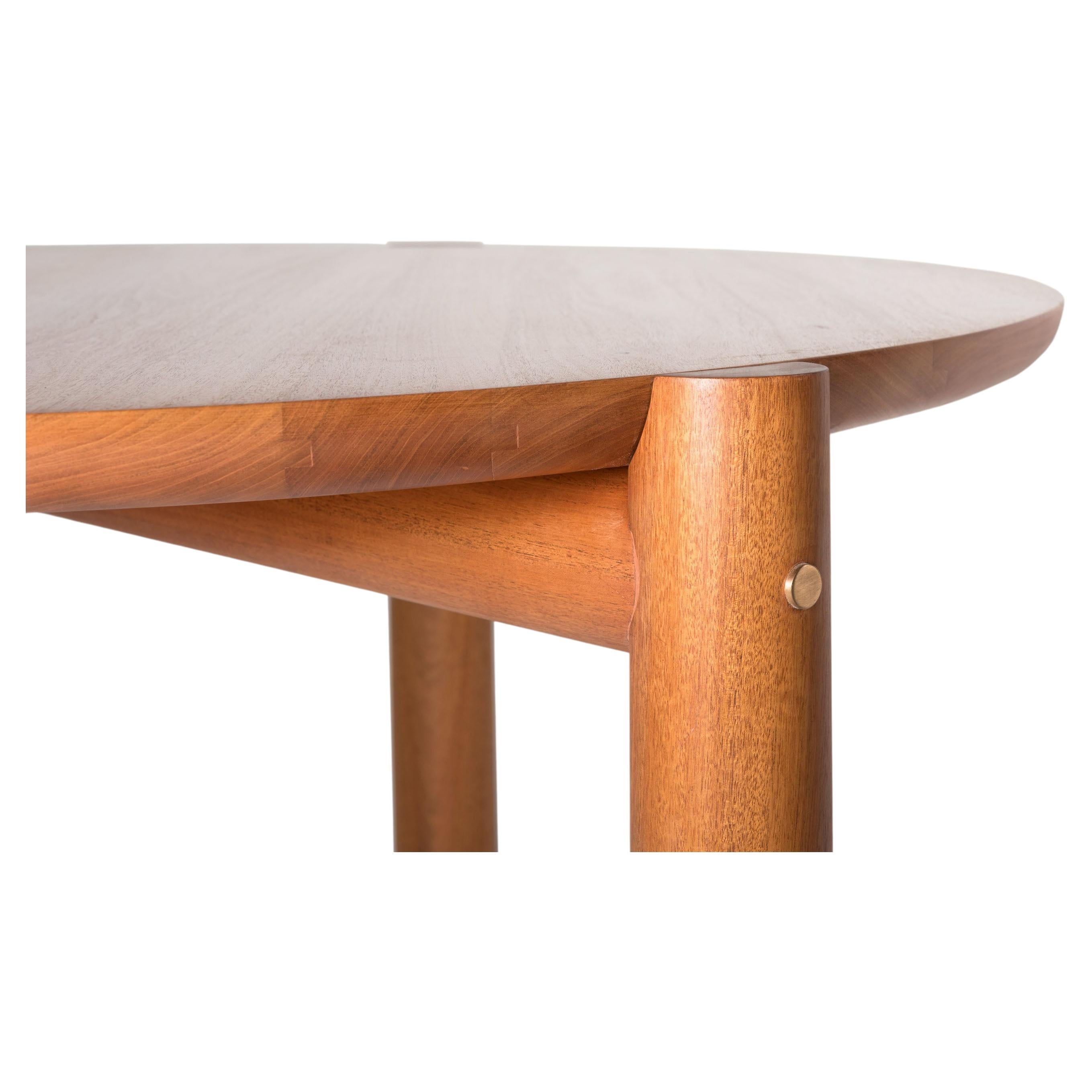Table with a round top and three legs brought together with a clean and fine construction. It boasts fine cabinetmaking with its very beautiful and precise joints and cuts. The bronze detail, a feature on the side of each leg, fastens the base and