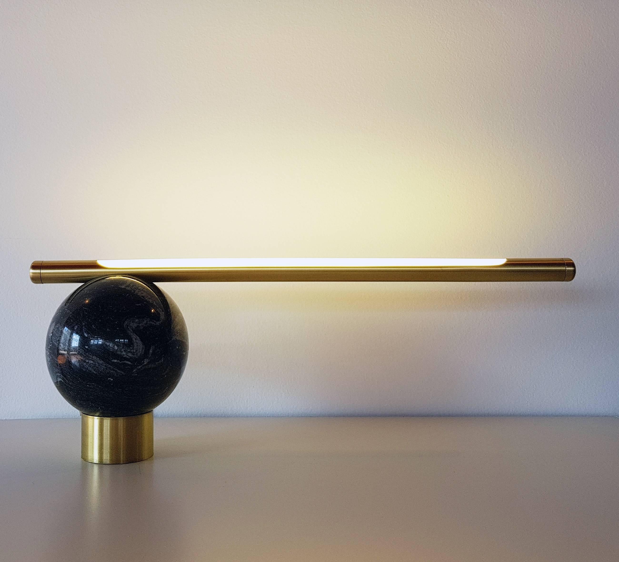 The Bubble table lamp is designed to be interactive with the user. Executed with a sphere carved by hand from a block of Black Marble found in the state of Espirito Santo, Brazil, has a brushed brass rod with a LED lamp inside. The adjustment is