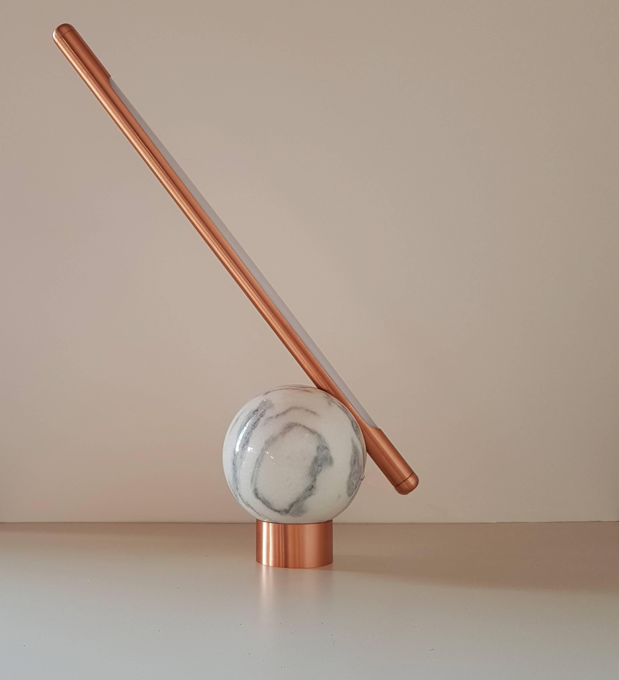 The Bubble table lamp is made of marble and copper, it's designed to be interactive with the user. Executed with a sphere carved by hand from a block of marble found in the state of Espirito Santo, Brazil, has a brushed Copper rod with a LED lamp