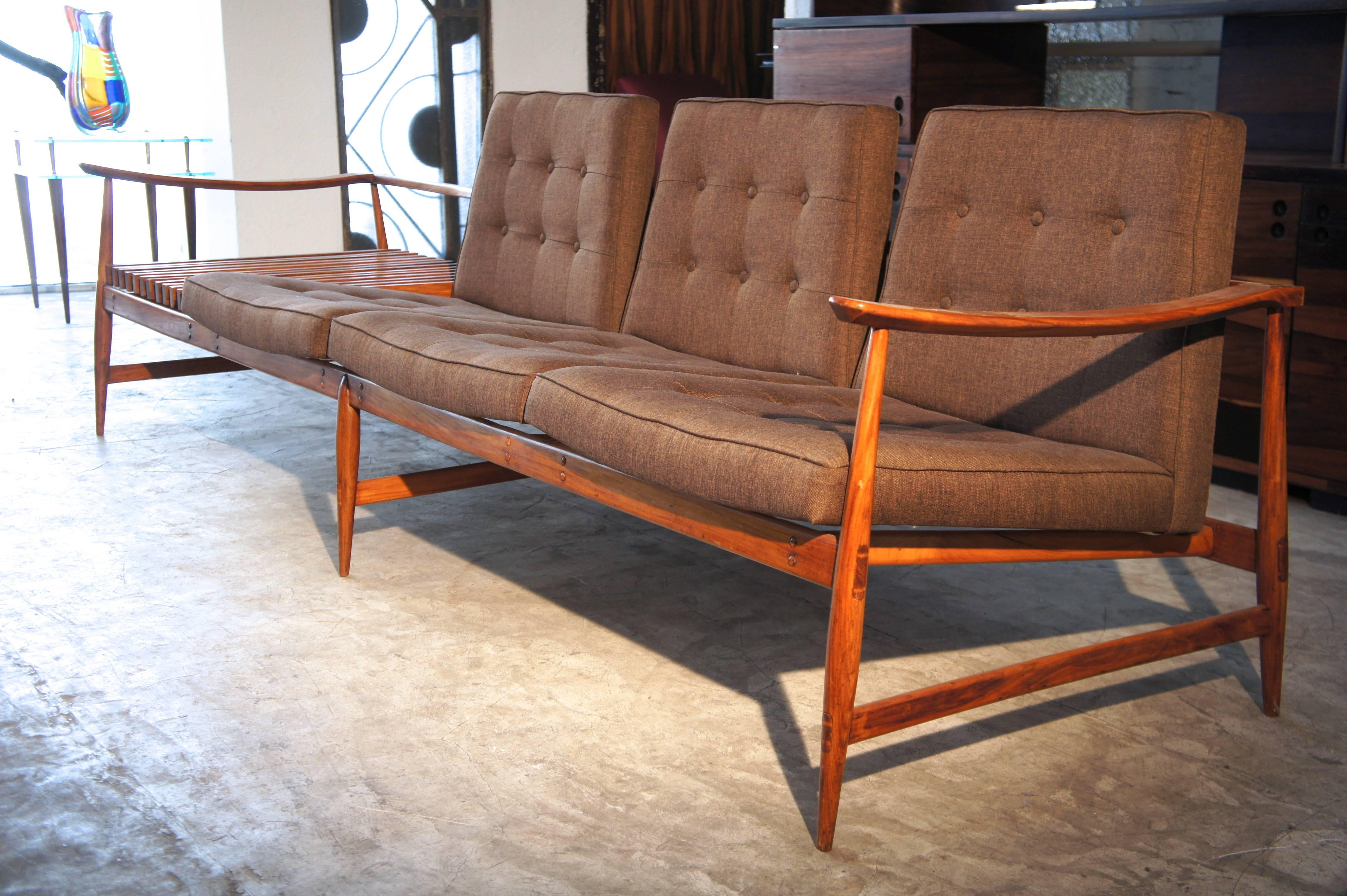This is a fine sofa made of caviuna wood by the Liceu de Artes e Ofícios. This amazing sofa features a moving magazine holder made of solid caviuna wood too. It has been recently restored and polished. This model is quite unusual because is has a