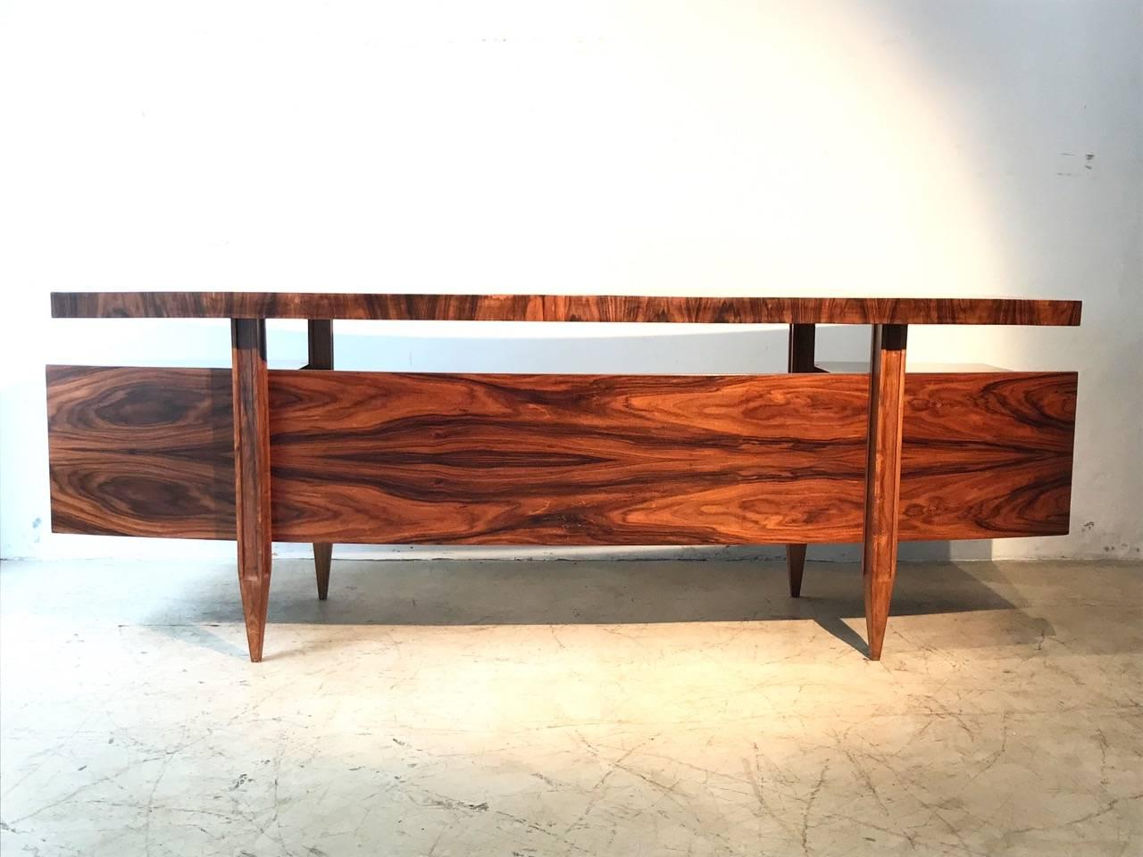 Amazing designed desk table that reminds a flying space ship with curved top floating like drawers with metal handles. This is very special item made by Cimo made of caviuna wood and it is very hard to find.