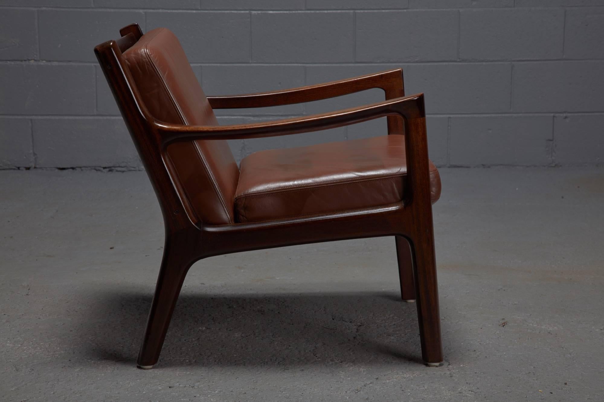 Designed by Ole Wanscher and produced by France & Son in Denmark, these Senator chairs are constructed with teak frames and brown leather seat and back cushions. Chairs sold as a pair.