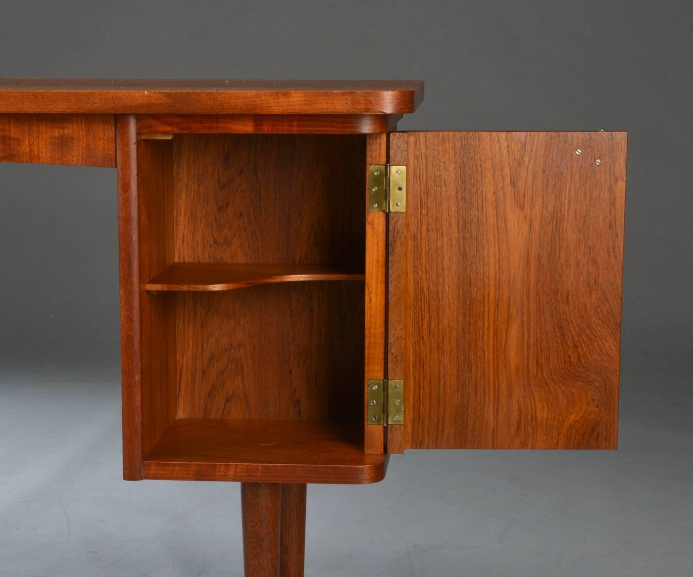 Small desk made of teak fitted with four drawers and cupboard with door fitted with brass handle. Includes key.