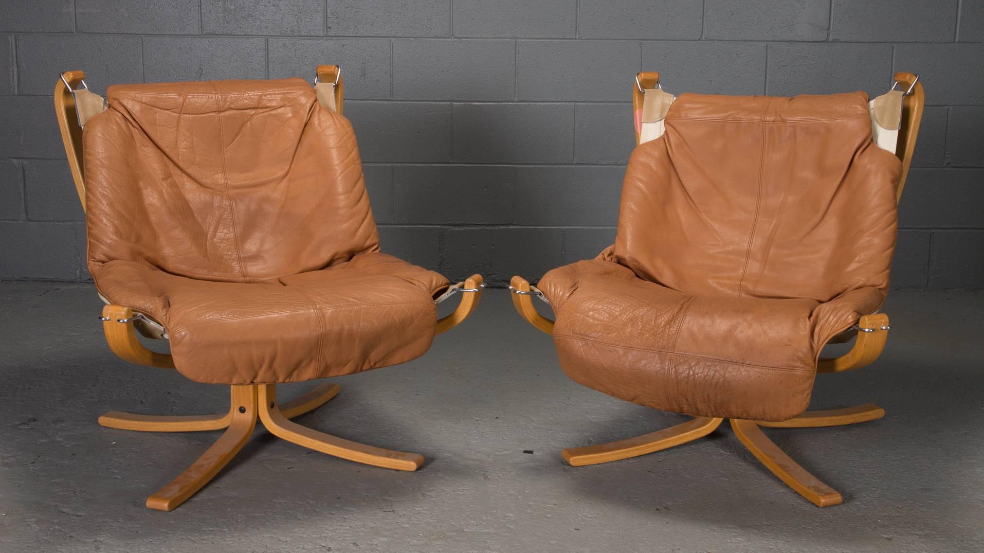 Designed in Norway by Sigurd Ressell for Vatne Mobler, this pair of Scandinavian bentwood sling chairs feature a low back, removable leather cushions, and a wood frame.