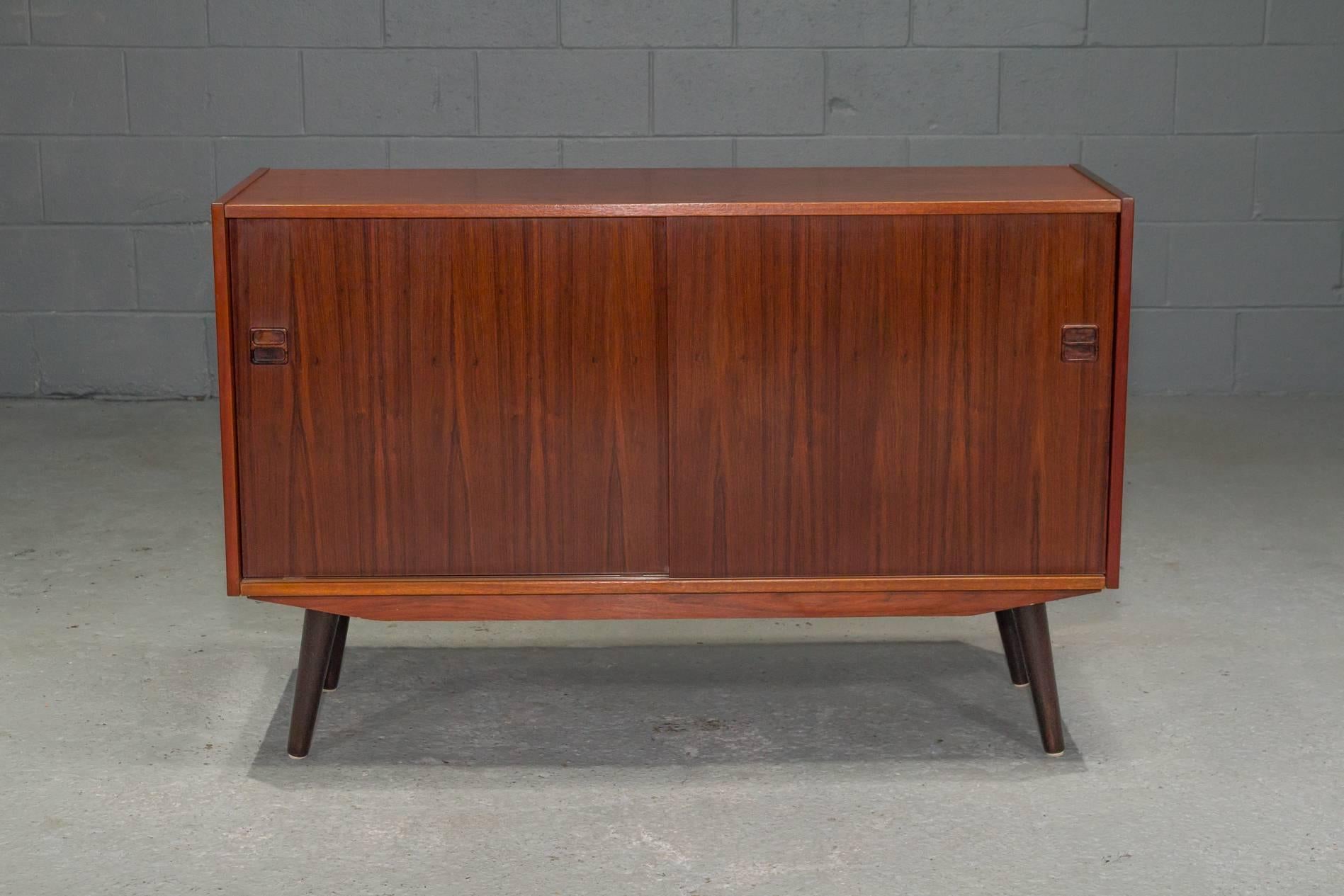 Small Two-Door Danish Modern Rosewood Sideboard on angled tapered legs. Sliding doors open to reveal adjustable open shelving.