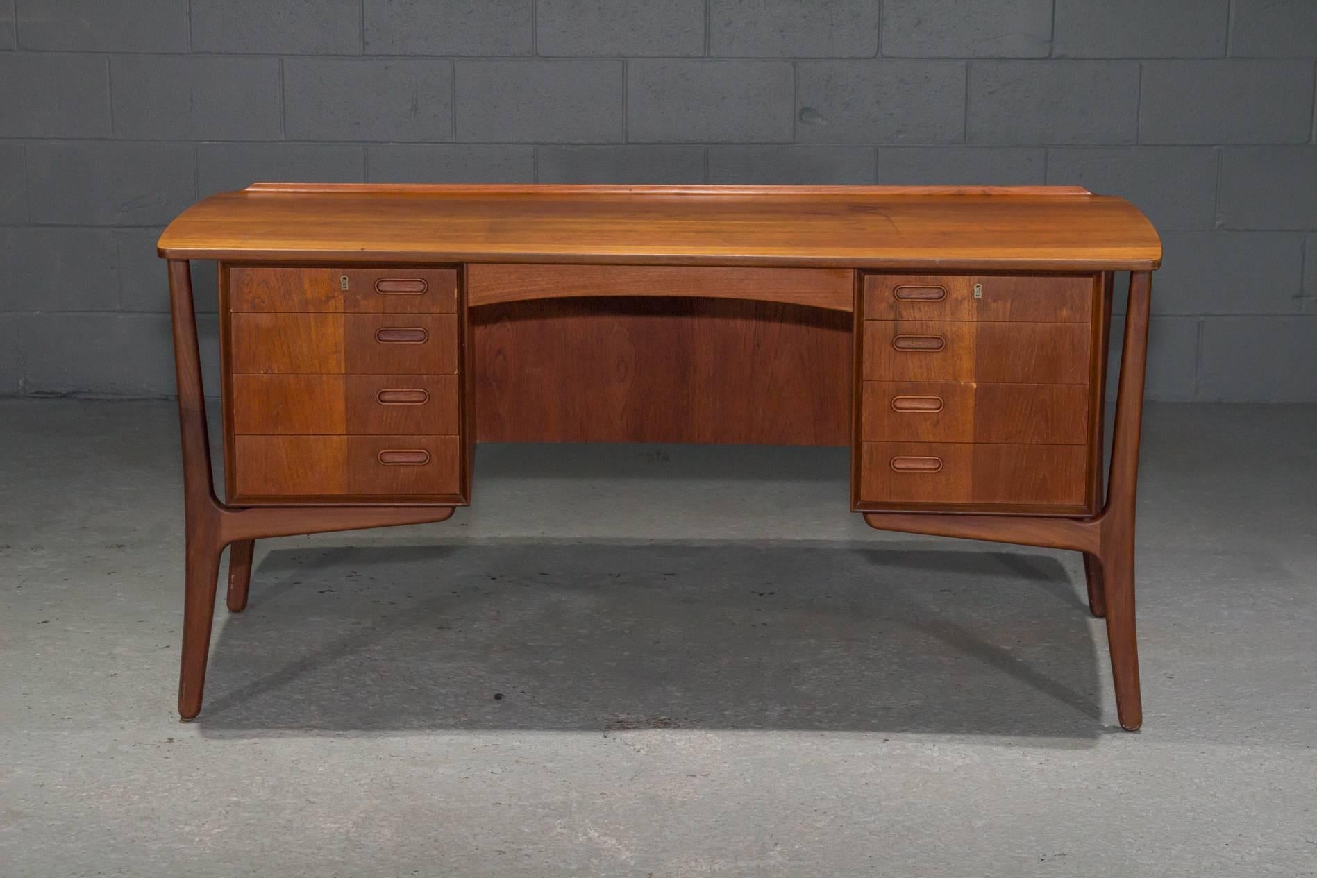 Danish Modern Teak Curved Desk. Four drawers with recessed pulls on either side with a large open shelf in the back as well as small cabinet with a door. Key not included. 