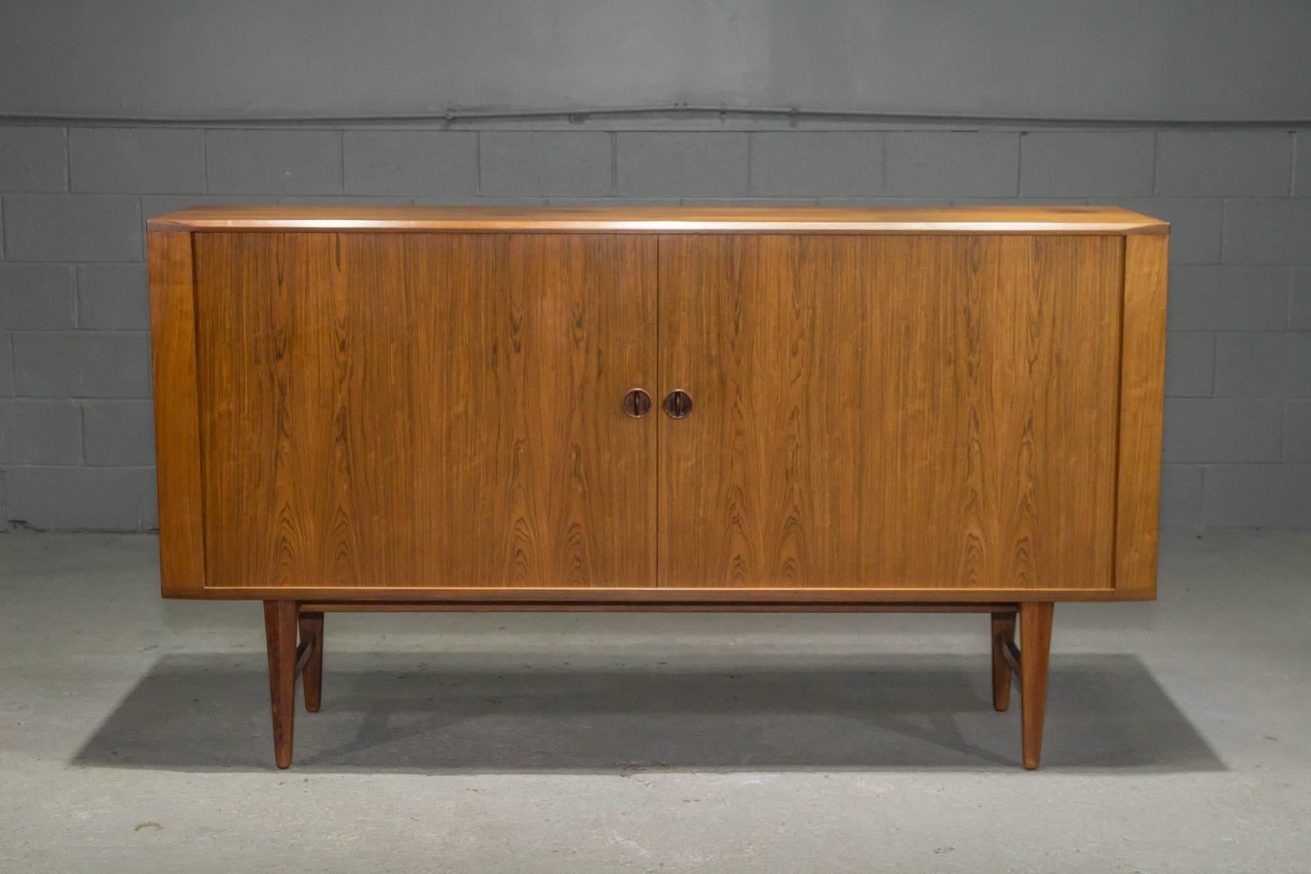 Danish Modern High Rosewood Sideboard with Tambour Doors. Doors open to reveal three large storage areas with two adjustable shelves on either side, as well as an adjustable shelf and four felt-lined cutlery drawers in the middle. Beautifully