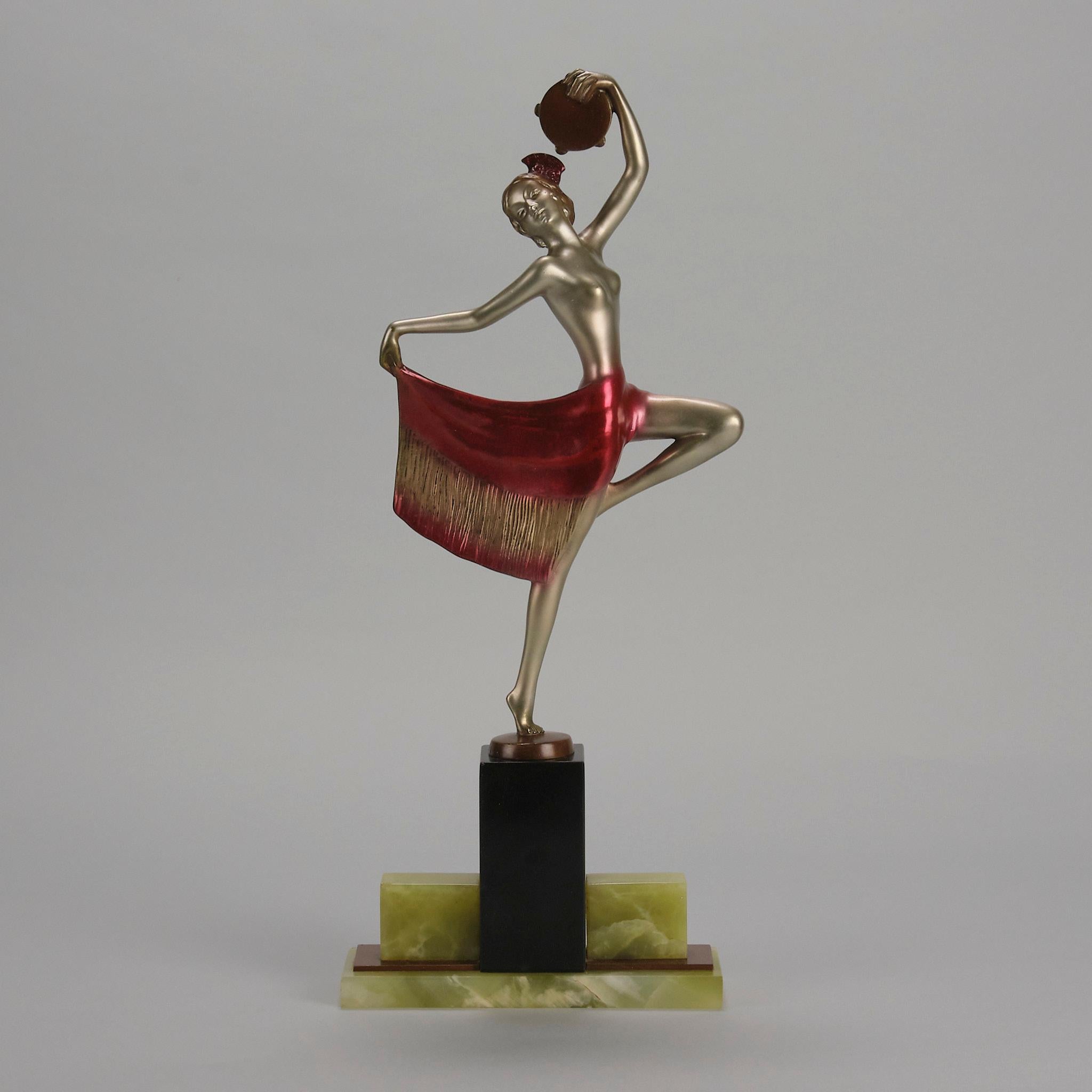 Eine attraktive, kalt bemalte Bronzefigur aus dem frühen 20. Jahrhundert, die eine junge Tänzerin in auffälliger Pose darstellt, die in einer Hand ein Tamburin hält, während sie den Saum ihres Rocks mit einer großen roten Blume im Haar