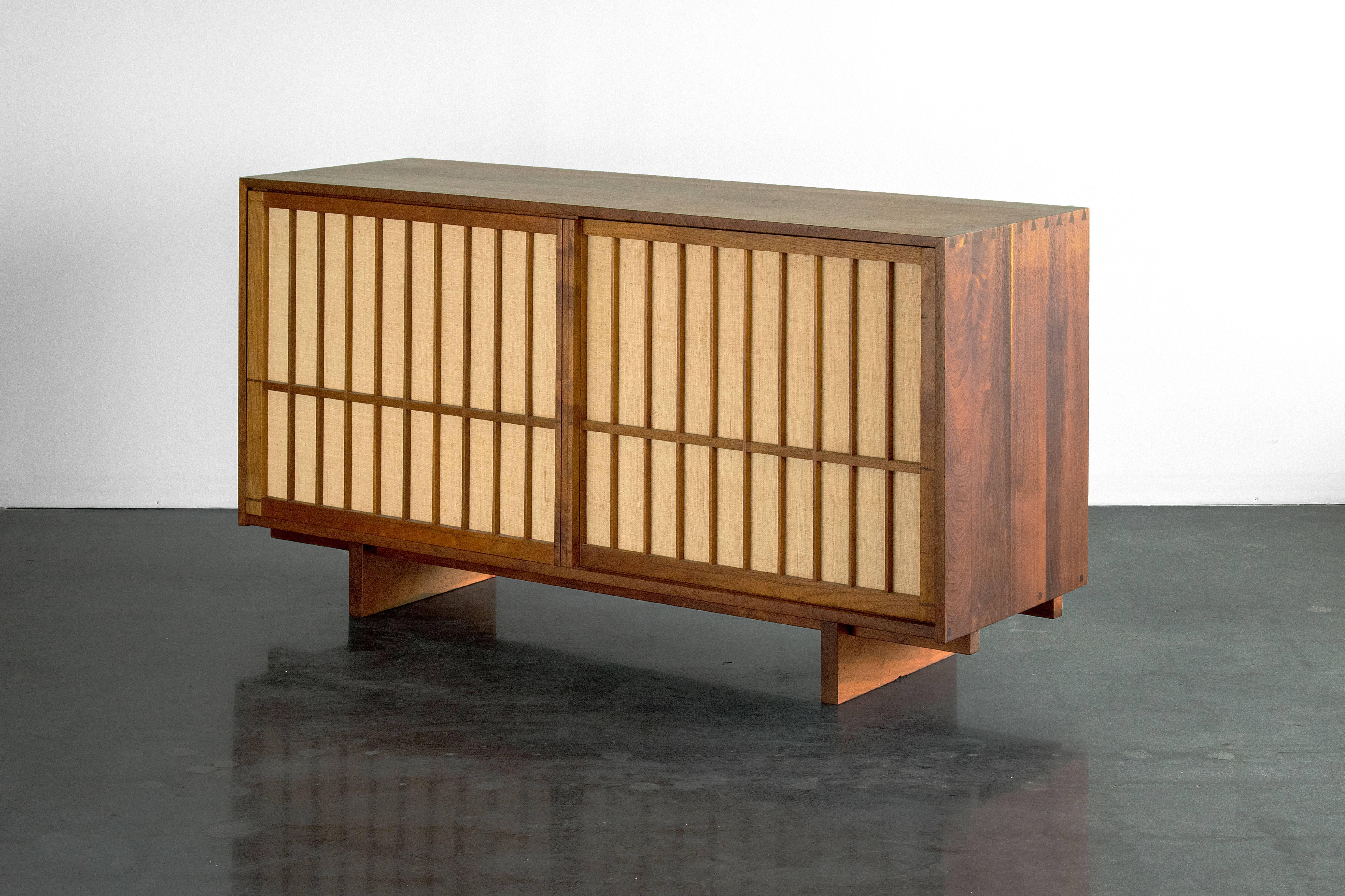 A beautiful and practical cabinet handcrafted in walnut and pandanus cloth. Four drawers on each side. Produced by American Nakashima studios, before 1958. Includes a letter of authenticity from Mira Nakashima.

  