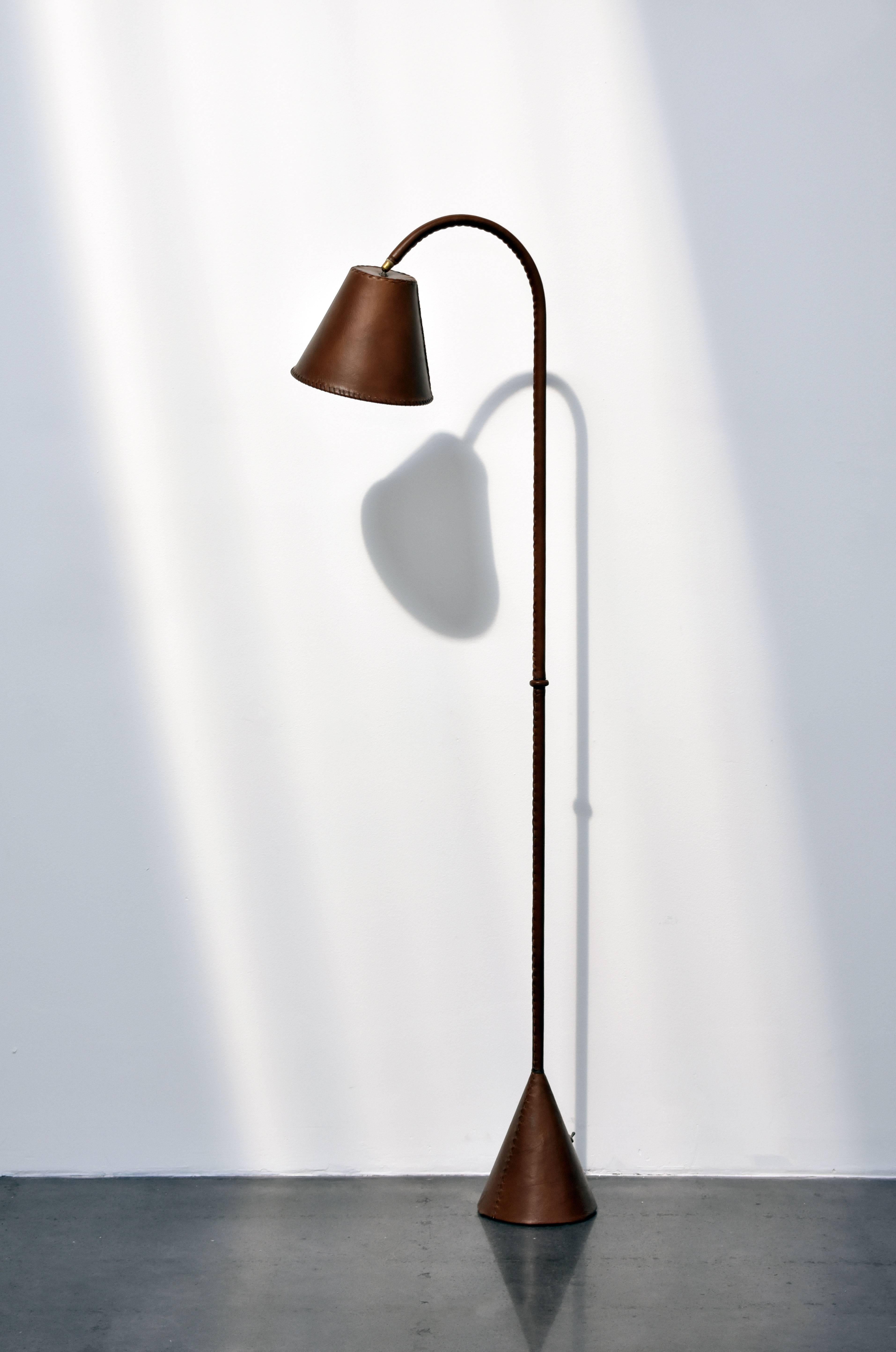 A French standing floor lamp. Manufactured in France, circa 1950. Lavishly clad entirely in saddle-stitched leather.