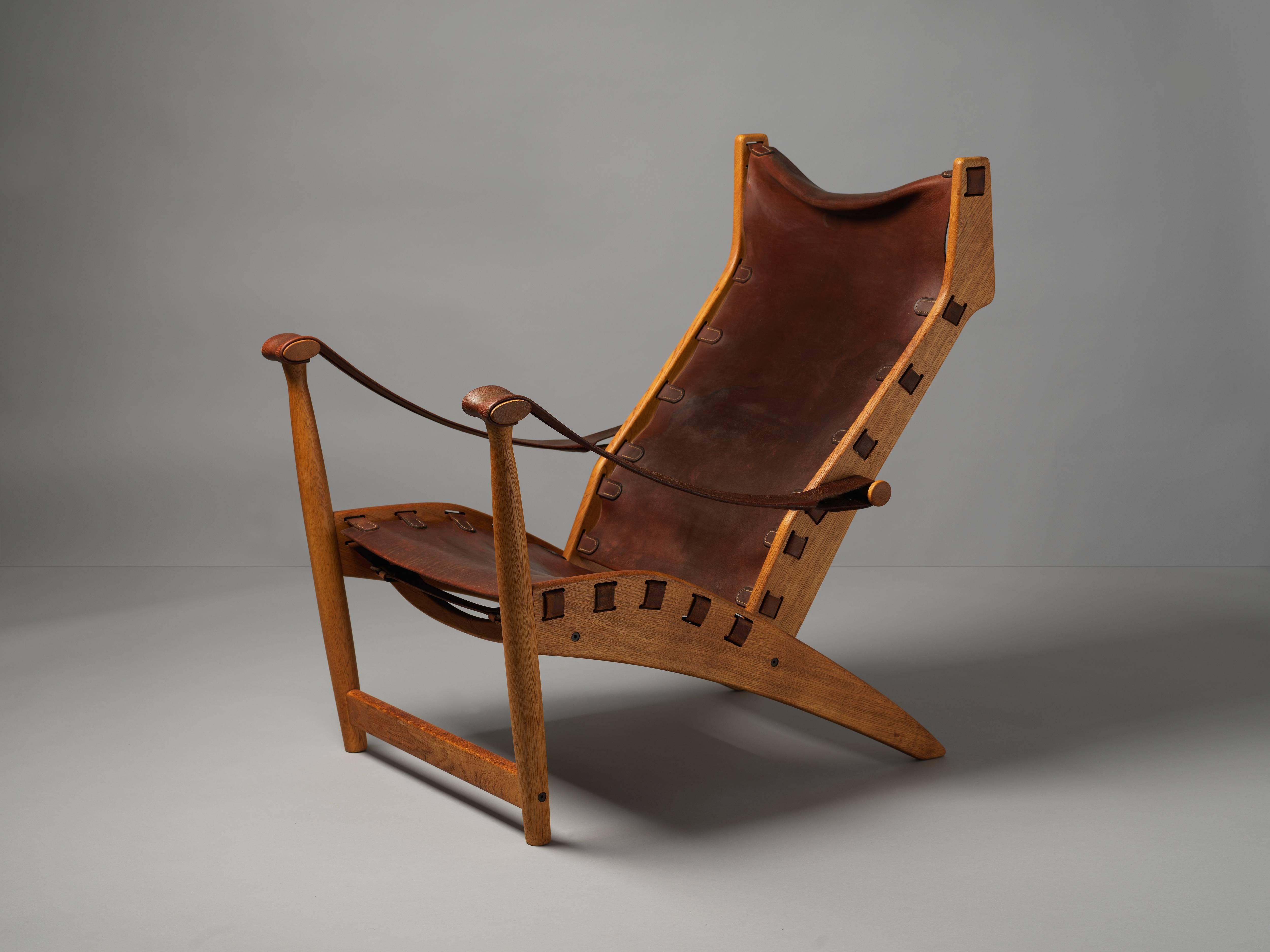 A Danish lounge chair in brown natural leather and oak, produced by Niels Vodder. The dark brown original aged saddle leather provides an elegant contrast to the patinated original oakwood. A fine example of Danish modern from one of the most