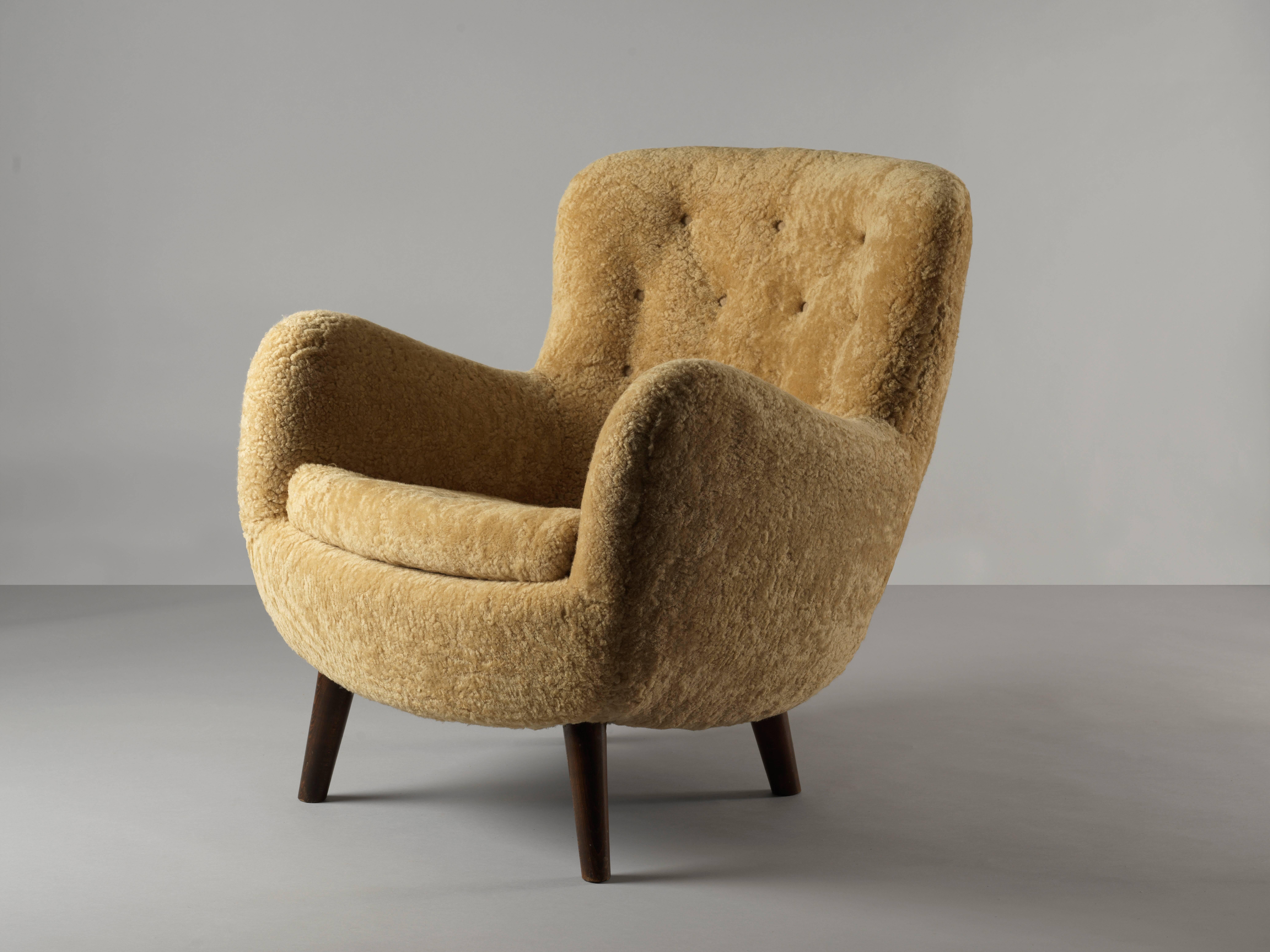 An example of early Danish modernism. Schlegel plays with the round form in a way that draws parallels to works such as the Egg chair that Jean Royere designed a decade later.

Upholstered in beige sheepskin contrasting dark wooden legs.

Frits