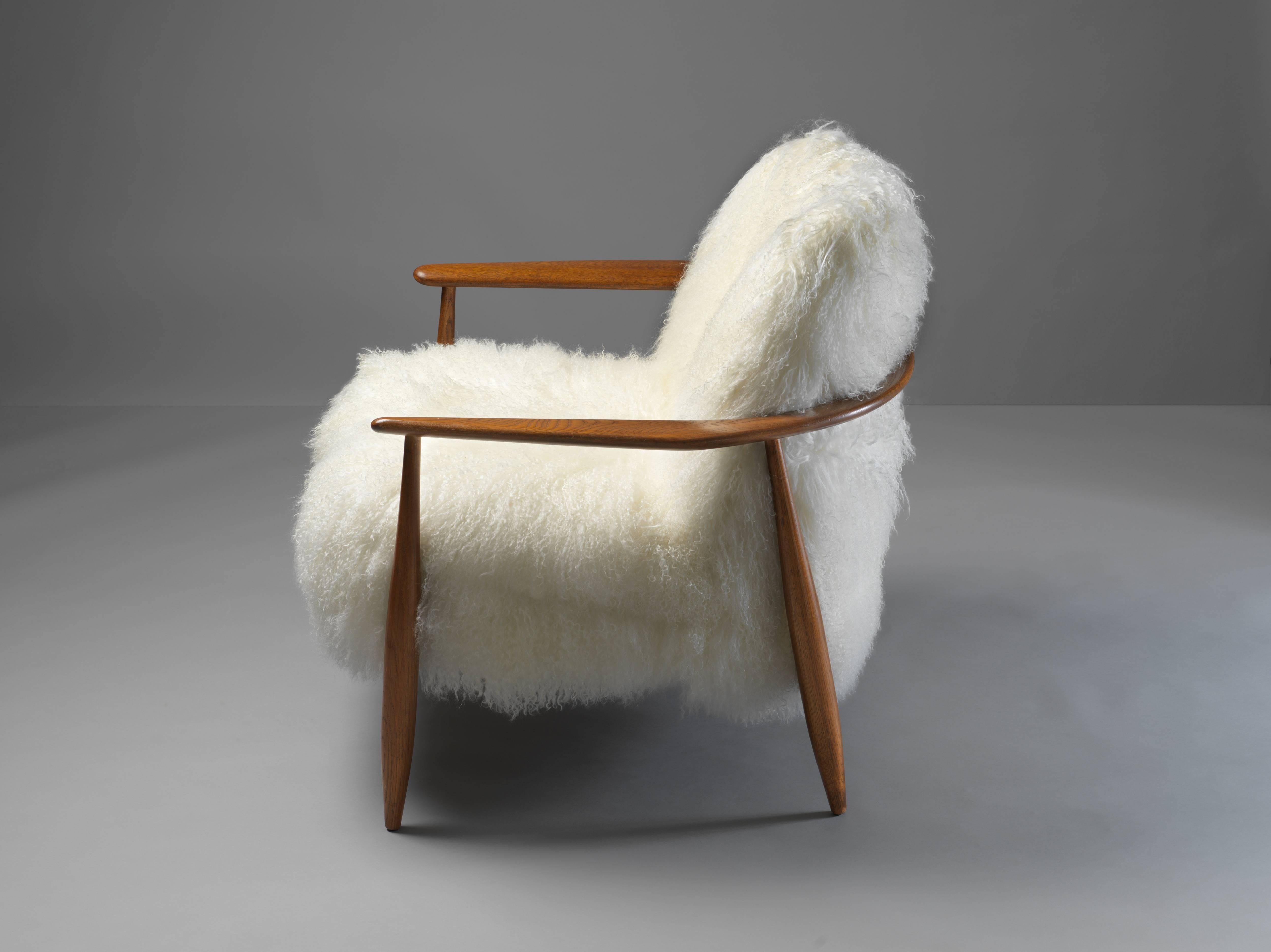 An organic lounge chair, design attributed to Danish designer Ib Kofod-Larsen. Upholstered in long lambskin, frame of stained oak. Presumably manufactured by Swedish Säffle Möbelfabrik.