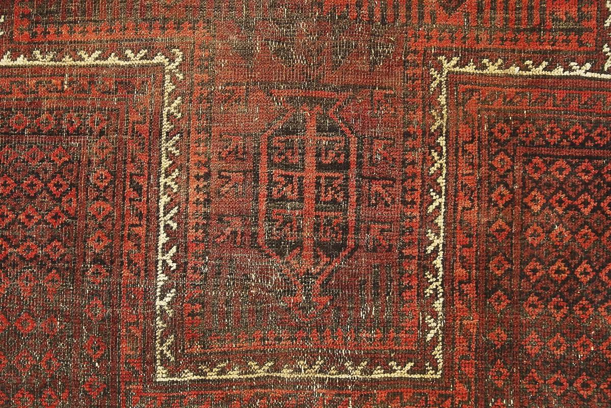 This handmade Baluch rug was manufactured in the early 1920th. The rug is in traditional deeply red color with geometric, tribal pattern. This hand-knotted carpet is unique. Baluch rugs are woven in the wider area of Baluchistan, which covers the