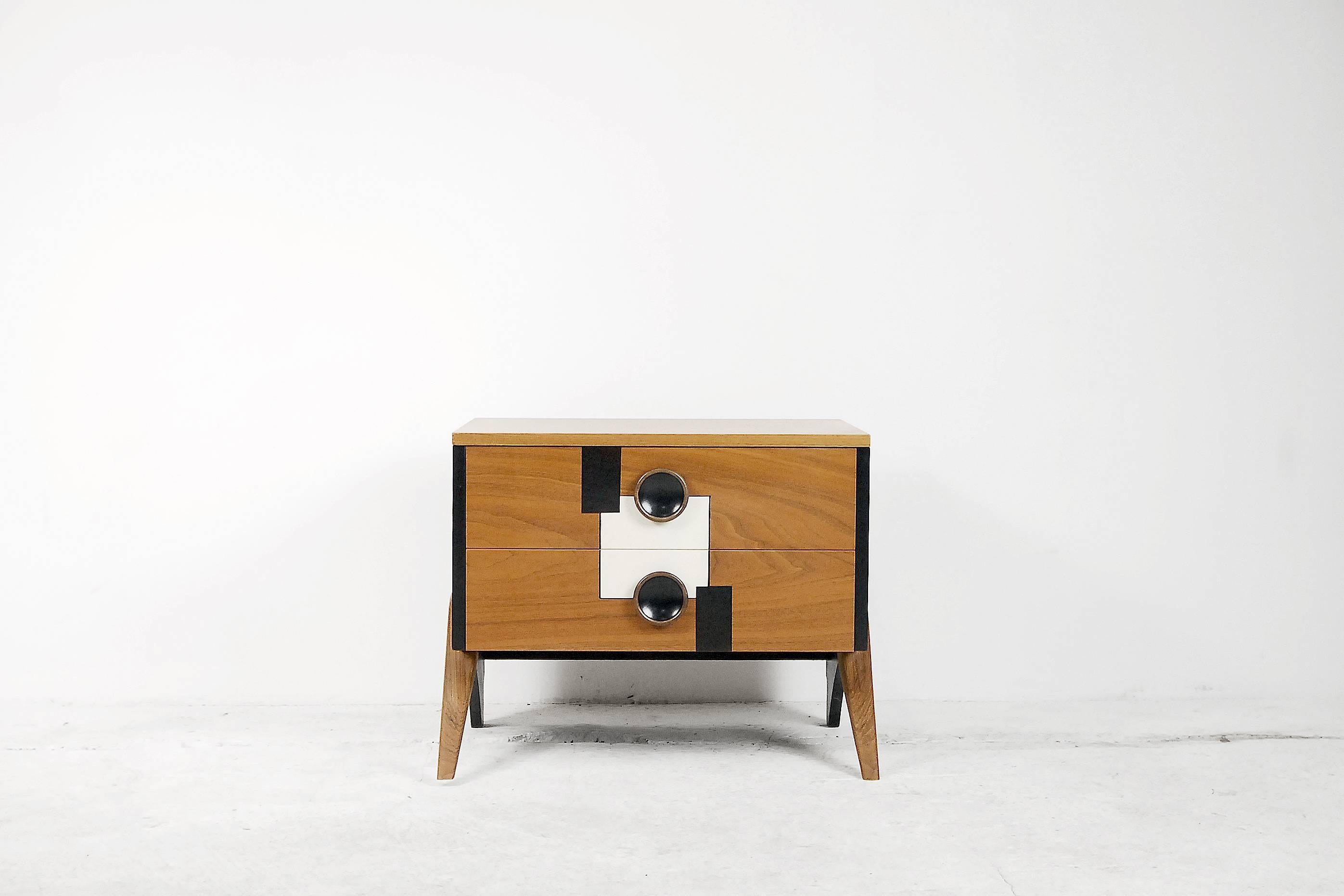 This mid-century modern small cabinet was manufactured in Scandinavia during the 1960s. It has a Space Age form and is made from walnut and veneer. The front is decorated with a hand-painted, geometric pattern, an the piece has a two drawers and