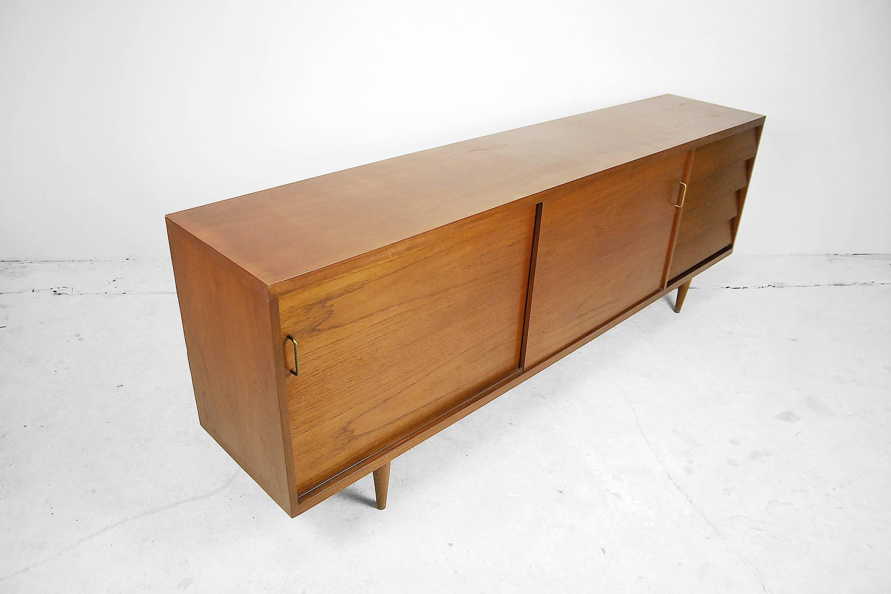 This long sideboard was manufactured in Denmark, during the 1960s. It is made from solid teak and teak veneer with a strong grain. It has a two sliding doors and four drawers.