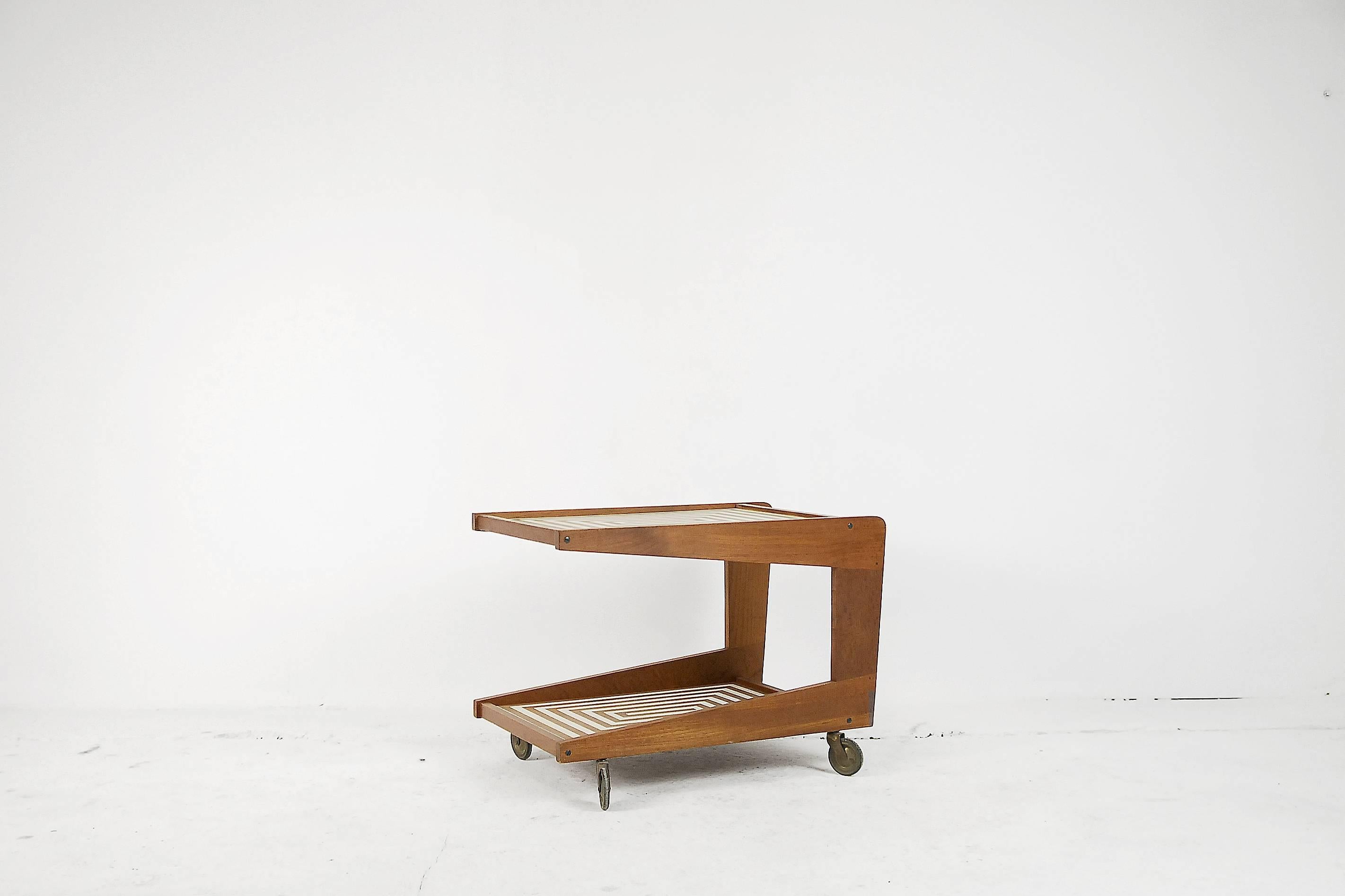This cocktail trolley in solid teak was manufactured in Denmark, during the 1960s. It has two table tops with a hand-painted labyrinth pattern in midcentury style.