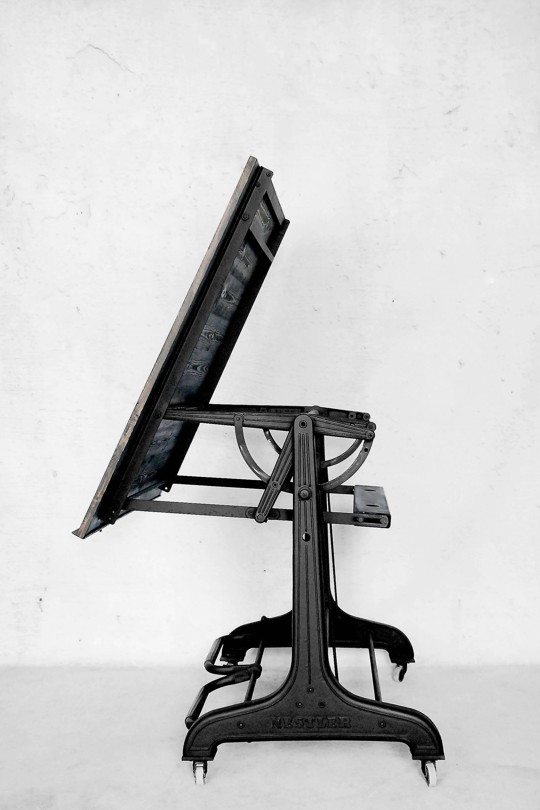 This drawing table was manufactured in Germany and designed by Nestler during the 1930s. It has a vintage antique frame made from cast iron. The table is adjustable and can be put in any positions and secured in that particular position; two pedals