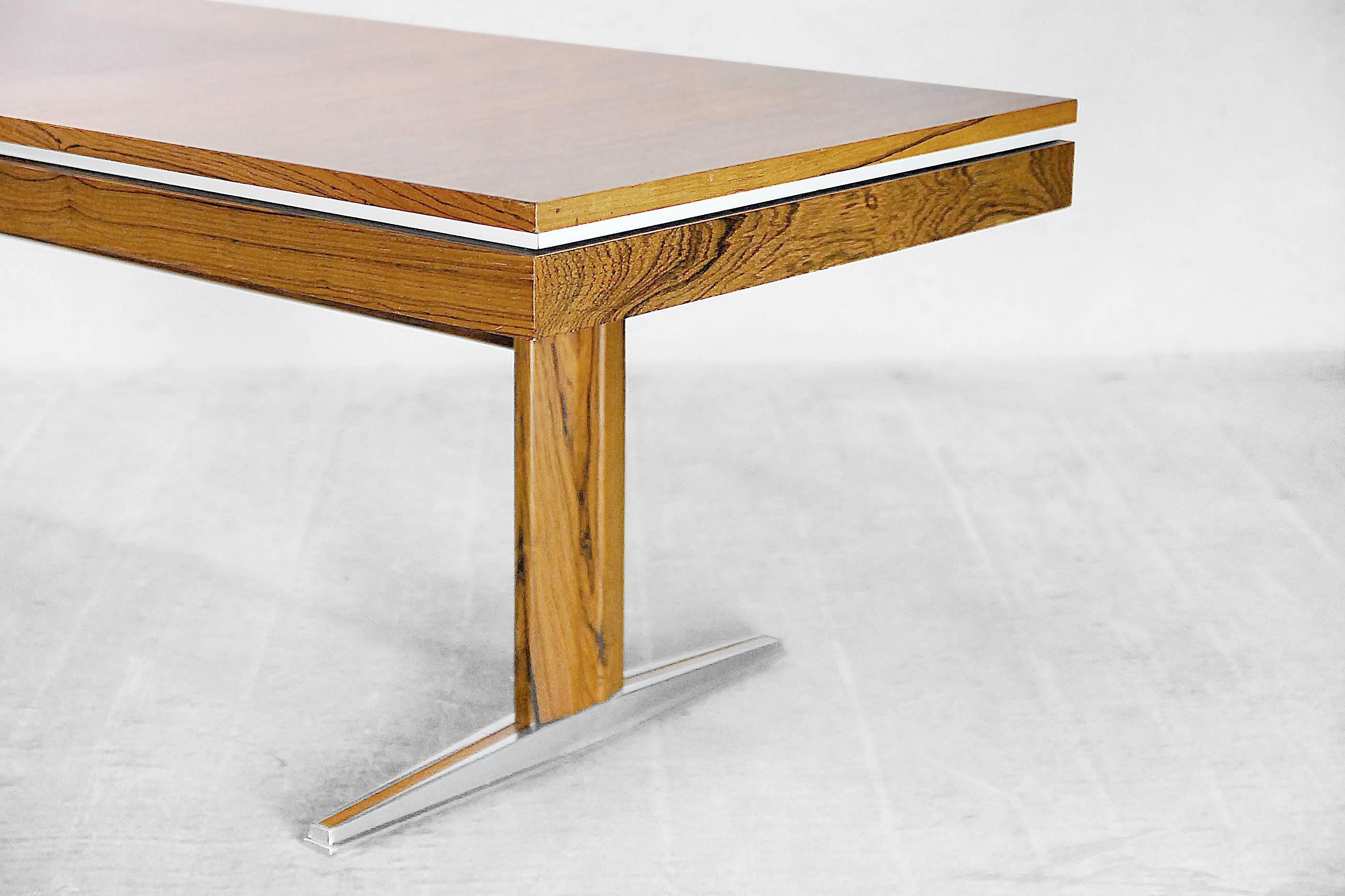 This rosewood folding side or dining table was manufactured by E.M.Ü in Germany during the 1960s. It has a two sliding tops and under them is a hidden shelf. Under the shelf there is a screw mechanism with a crank, which adjusts the height of top