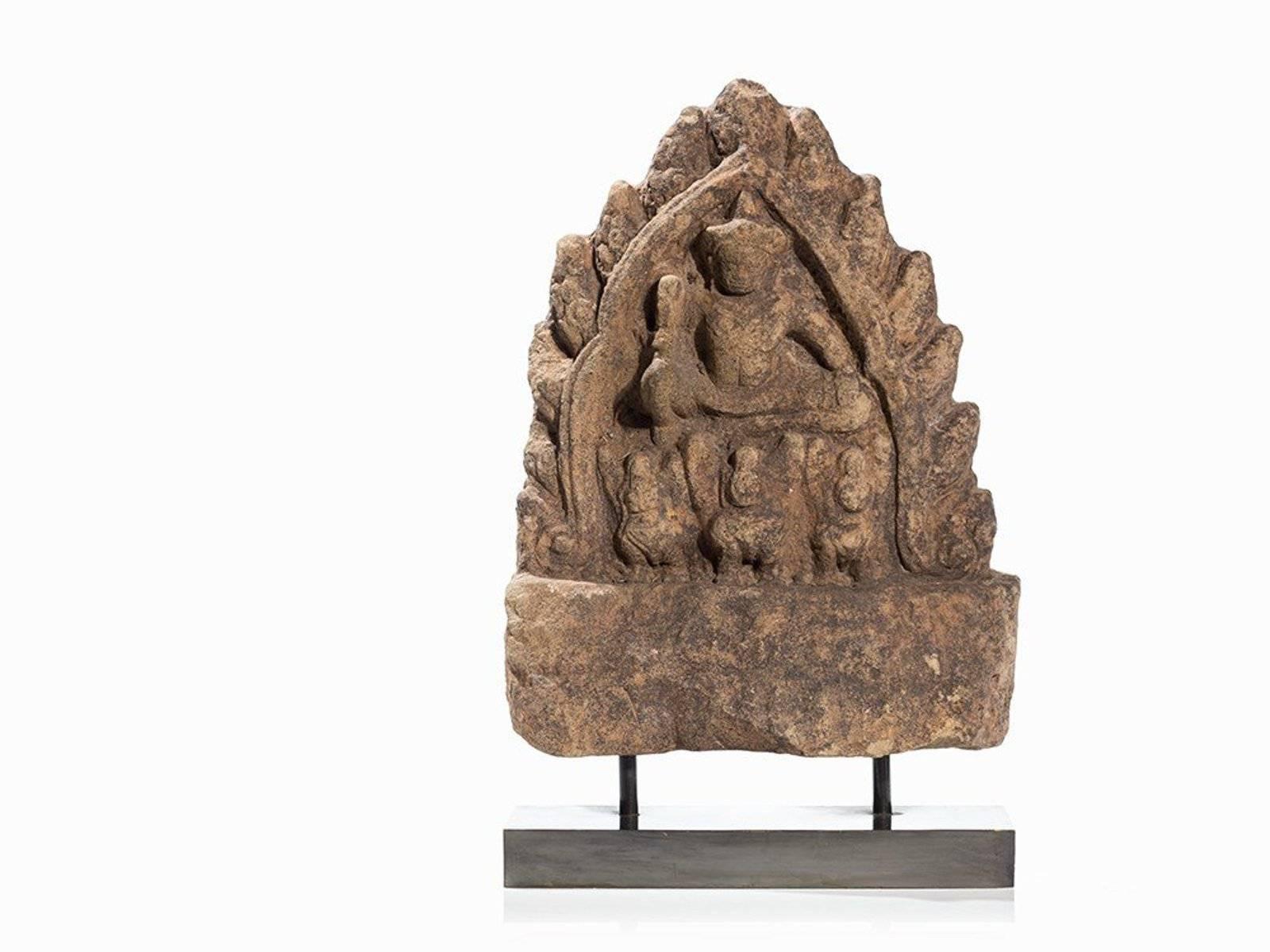 A superb sandstone figure of Indra
Cambodia, Khmer Kingdom, Angkor period, Bayon style, 12th-13th century

Superb Angkor Figure Indra, A triangular shaped stele with the depiction of Indra in the center of a flamed niche. Seated in royal ease on
