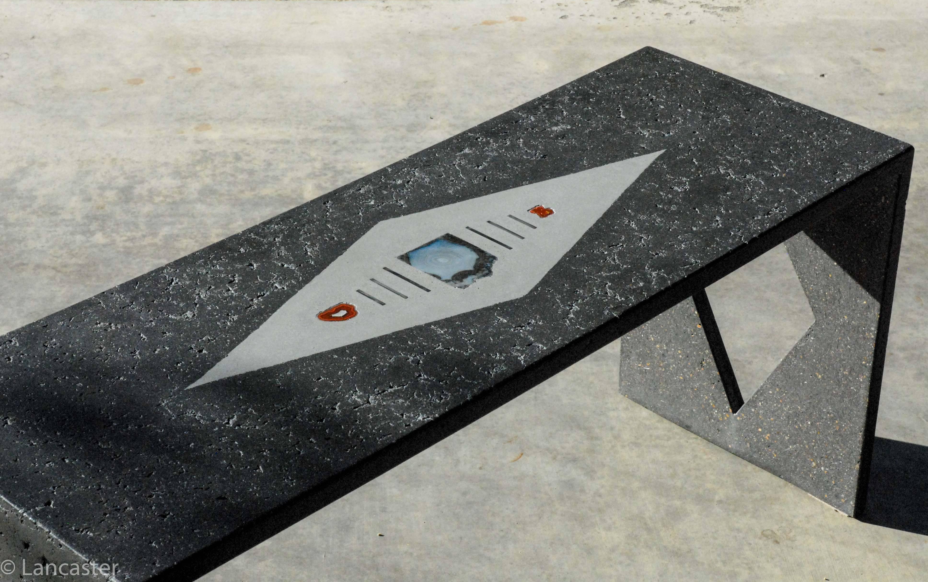 This contemporary concrete bench can be used for indoor or outdoor settings. The color shown is a graphite black and was created using a hand packed technique to provide a vein-like appearance often found in natural stone like marble. This artisan