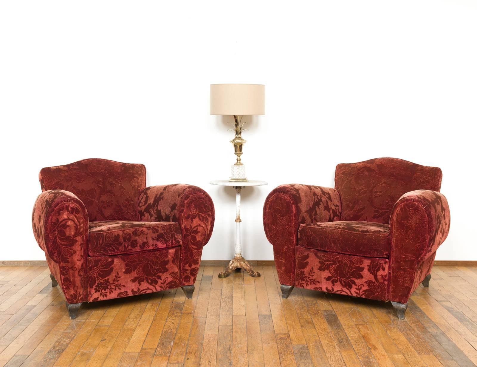 Set of two French club chairs dating from the 1950s. Both chairs still have their original, red mohair velvet fabric decorated with an beautiful, flowery pattern. The back has been finished of with rivets. 

Both chairs show light user marks. Overal