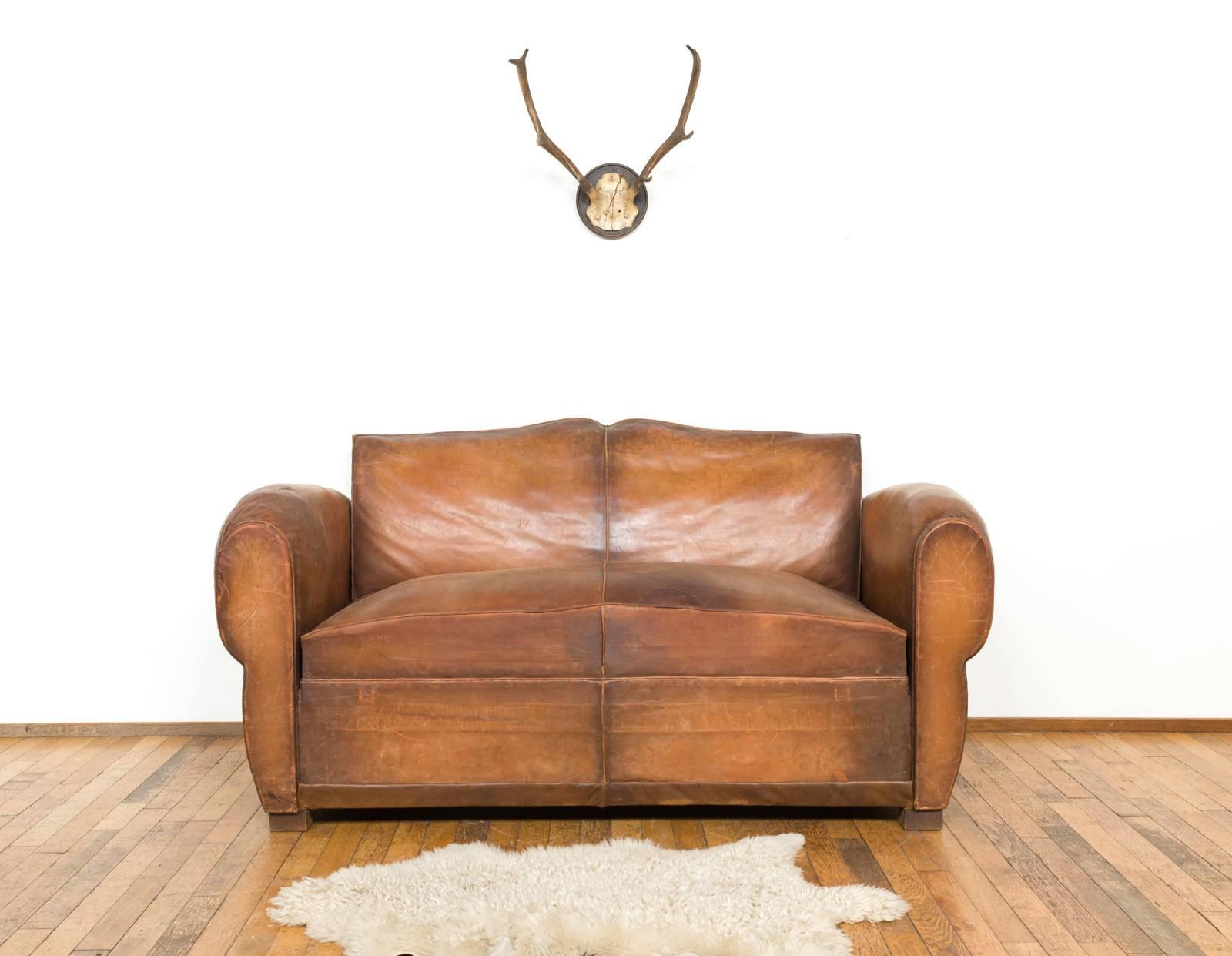 Beautiful French ‘Moustache’ clubsofa made in the 1930s-1940s. The sofa is made out of cognac leather. The leather is well worn en has a beautiful patina. There have been a couple of repairs to the leather which can be seen on the photos. 

The