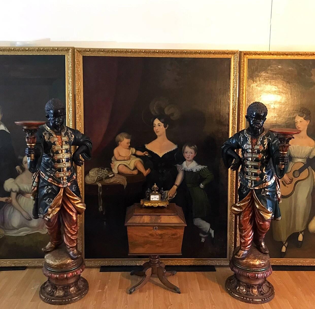 A Fine pair of 19th century Venetian Blackamoor torchere stands, carved wood with gesso, gilt and polychrome decoration, with glass eyes, each wearing elaborate costumes and holding a tazza in one hand, on raised circular socle plinths, truly