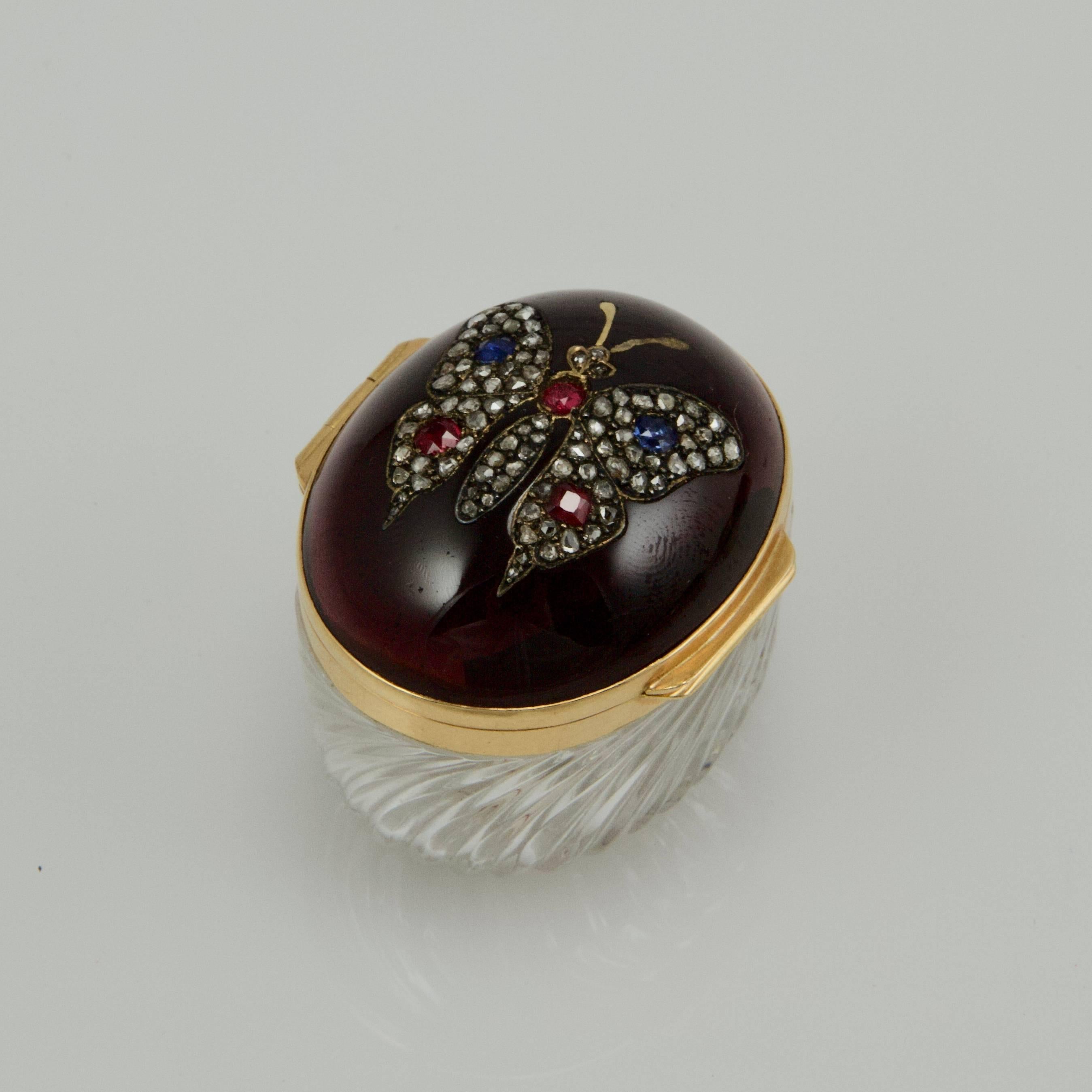 Cover presents a large garnet cabochon weight approximately 100-carats inset with a butterfly in diamond roses, sapphires and rubies. The rim mount in yellow gold. Base in crystal carved with swirling band.
French assays marks on the rim.
Typical