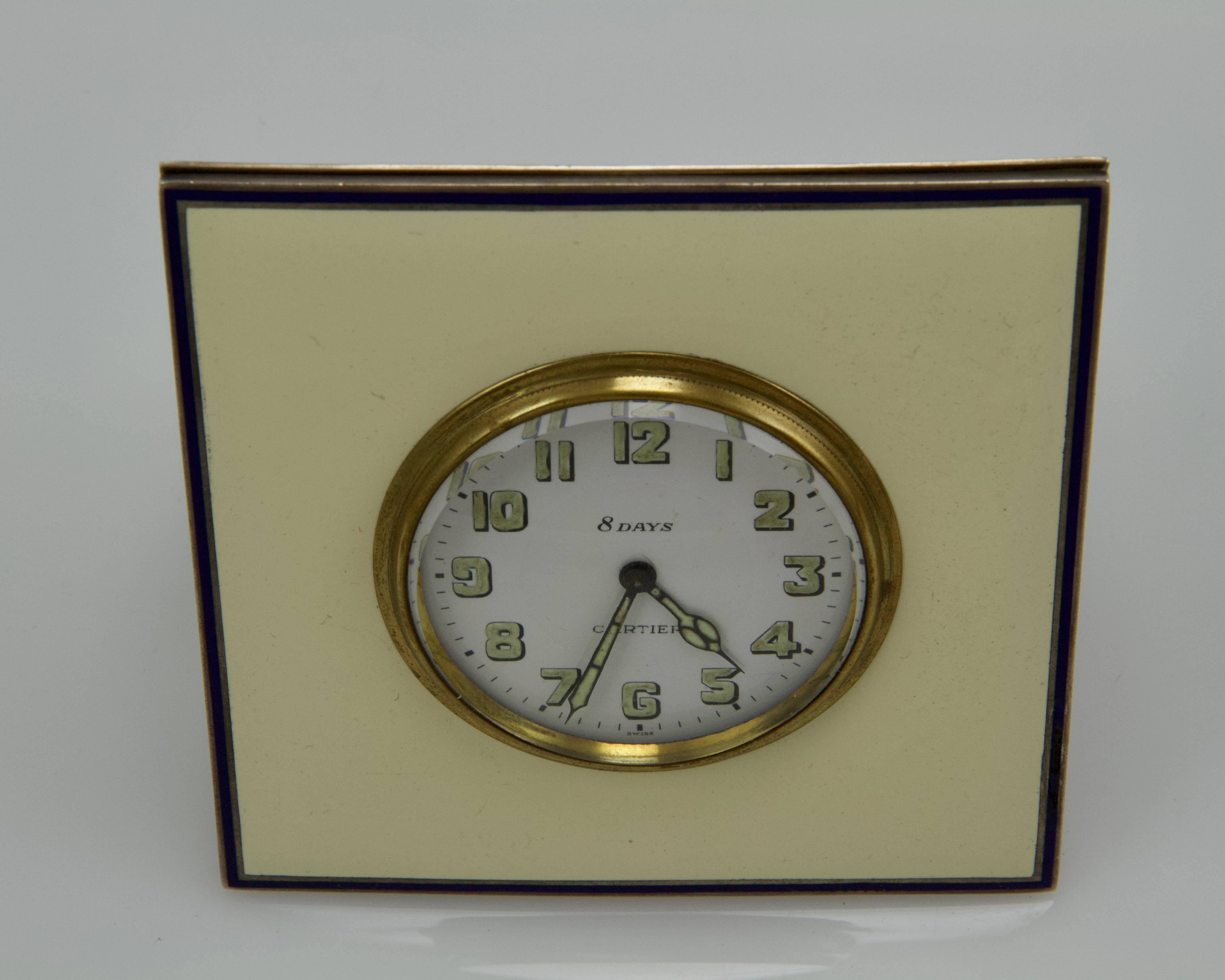 Circular white enamel dial signed Cartier with green fluorescent Arabic numerals and hands within a silver gilded bezel. The square silver case decorated with cream enamel bordered with navy blue enamel filet. On the back, inscription hand engraved: