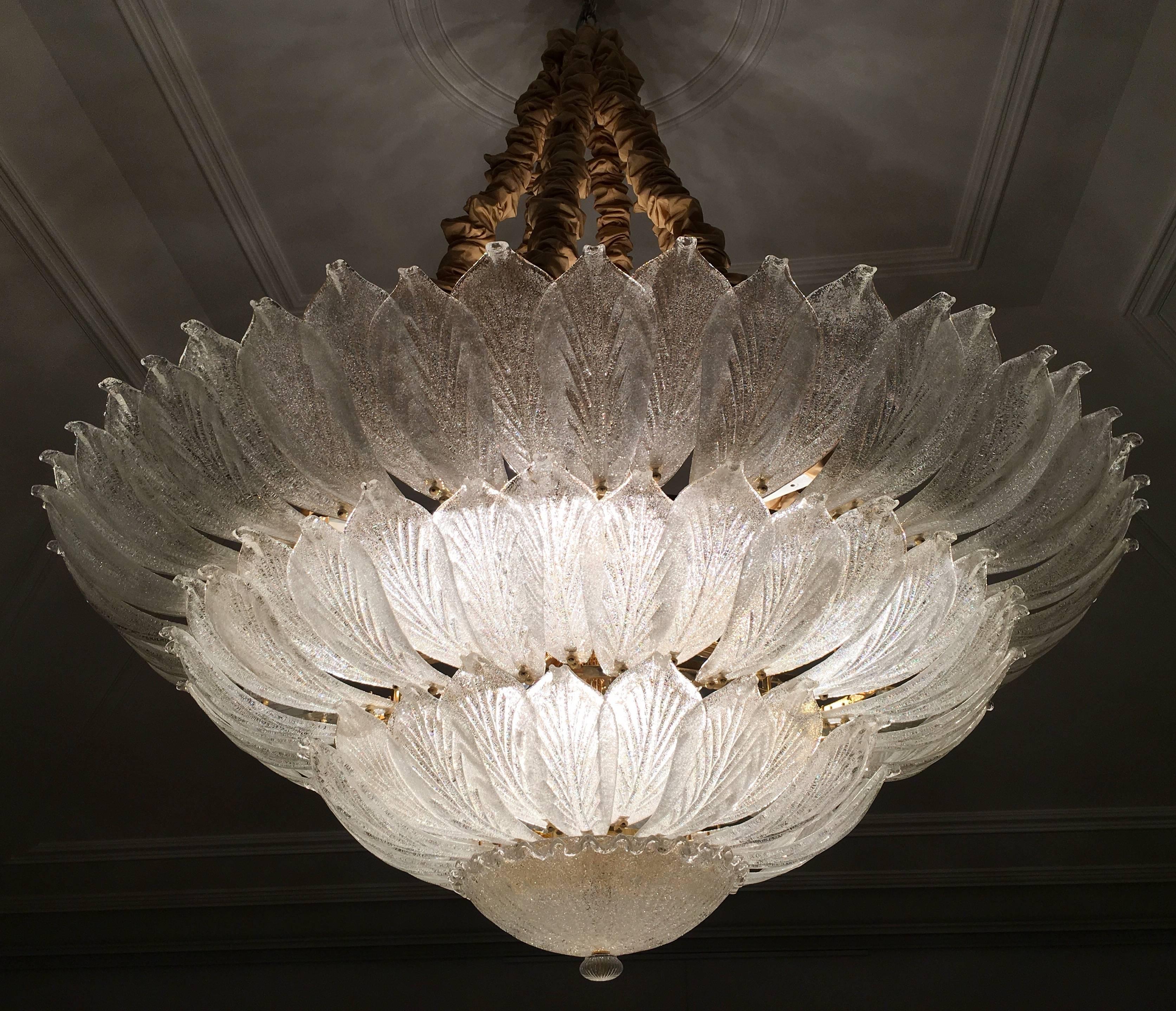 Realized in pure Murano glass, each chandelier consist of an incredible number of leaves. The structure is plated with gold. 18 lights spread a magical light. Measures: Diameter 156 cm, height 58 cm + chain. Also available are three ceiling lights