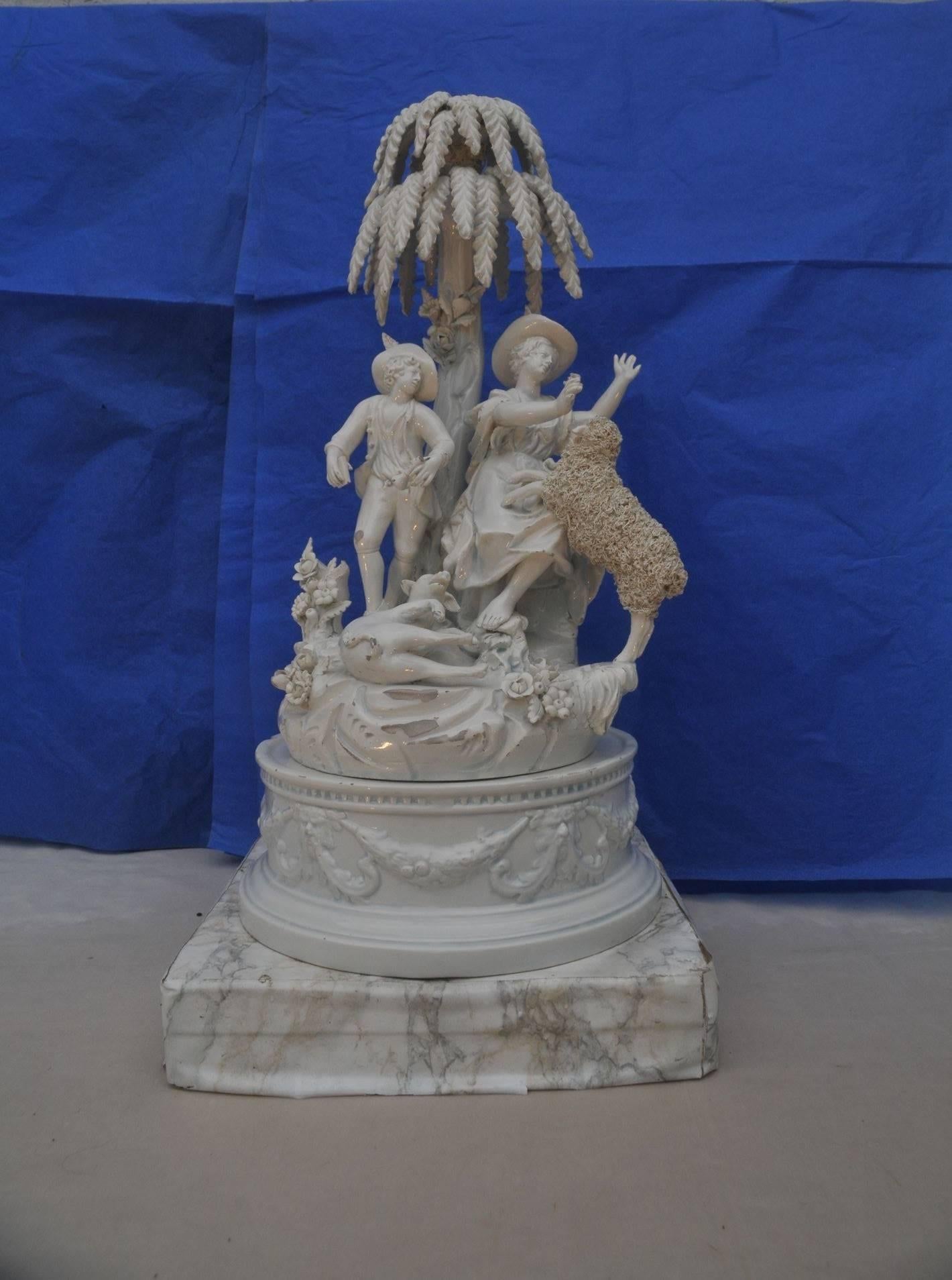 18th century.
Figuring a shepherd and a girl sitting on a rock work with a dog and a sheep under a tree.
Typical scene inspired by Marie Antoinette Louis XVI style.
Set on circular porcelain pedestal base.
Measures: H 15.60 inches (40