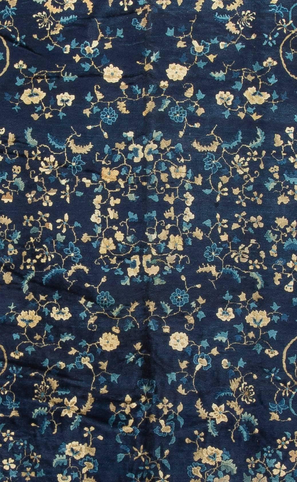 Un tapis chinois vintage des années 1940 tissé à la main. Le fond bleu marine profond présente de magnifiques motifs floraux délicats dans les tons ivoire et bleu. La bordure principale et les quatre bordures mineures qui entourent le champ donnent