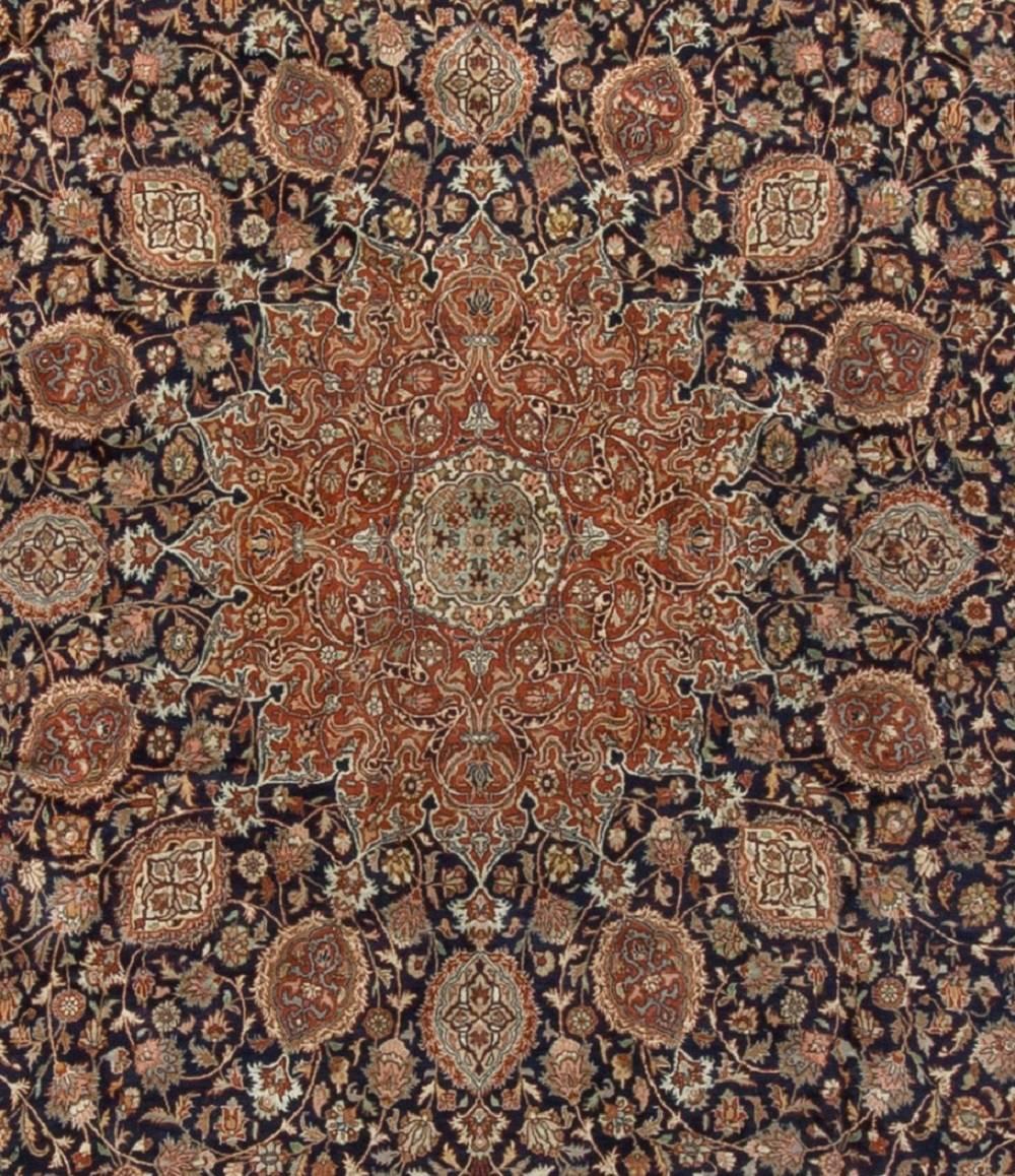 A vintage circa 1940s Persian Tabriz rug, the navy field filled with floral and vine designs encompassing a magnificent central floral themed medallion surrounded by detailed leaf designs. The main border in ivory repeating the floral theme and