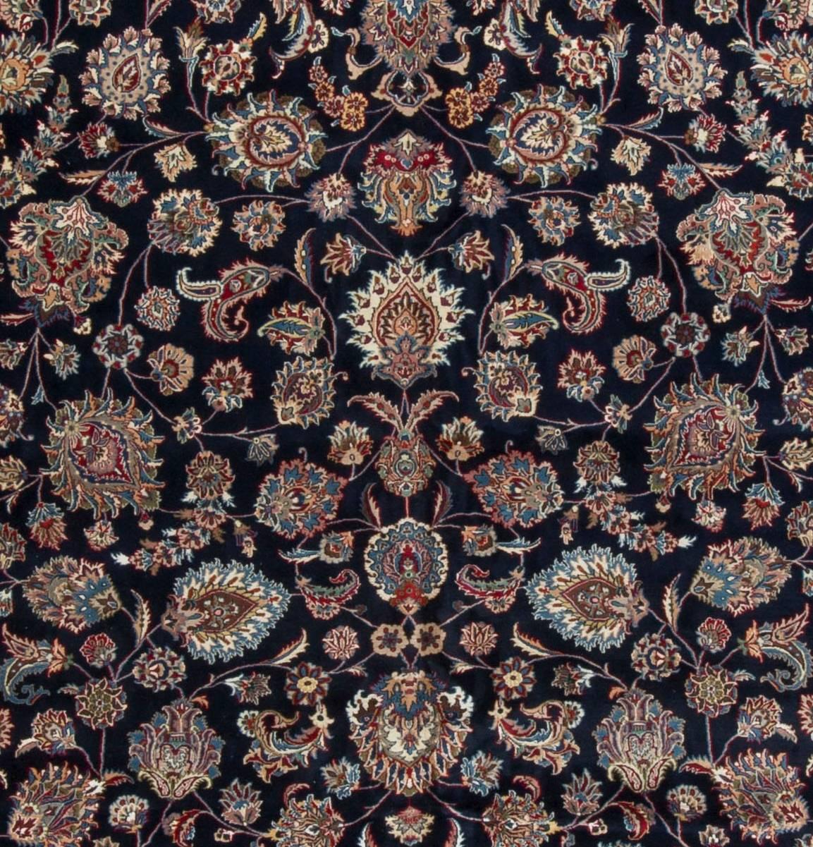Large Vintage Persian Semnan Rug circa 1940. The deep navy field filed with beautifully flower heads in a variety of colors woven in amazing detail that requires skills only learned over many years. The ivory border completes a perfect picture for