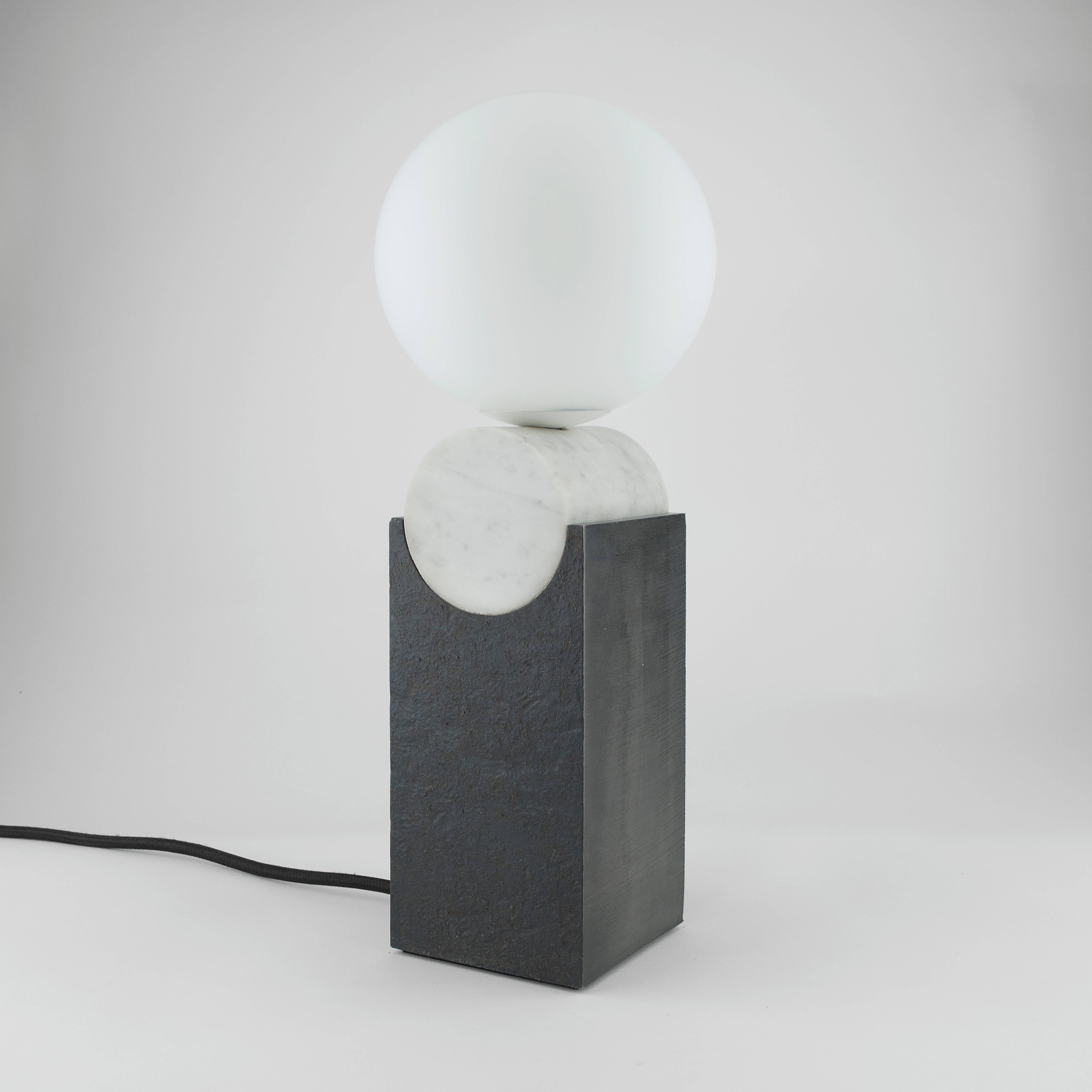 La lampe Monument Lamp de Louis Jobst - Circle est de haute qualité, sur mesure et fabriquée à la main à partir de matières premières solides. La base est finie avec une patine noire et découpée dans une billette d'acier de 90 mm d'épaisseur. Les