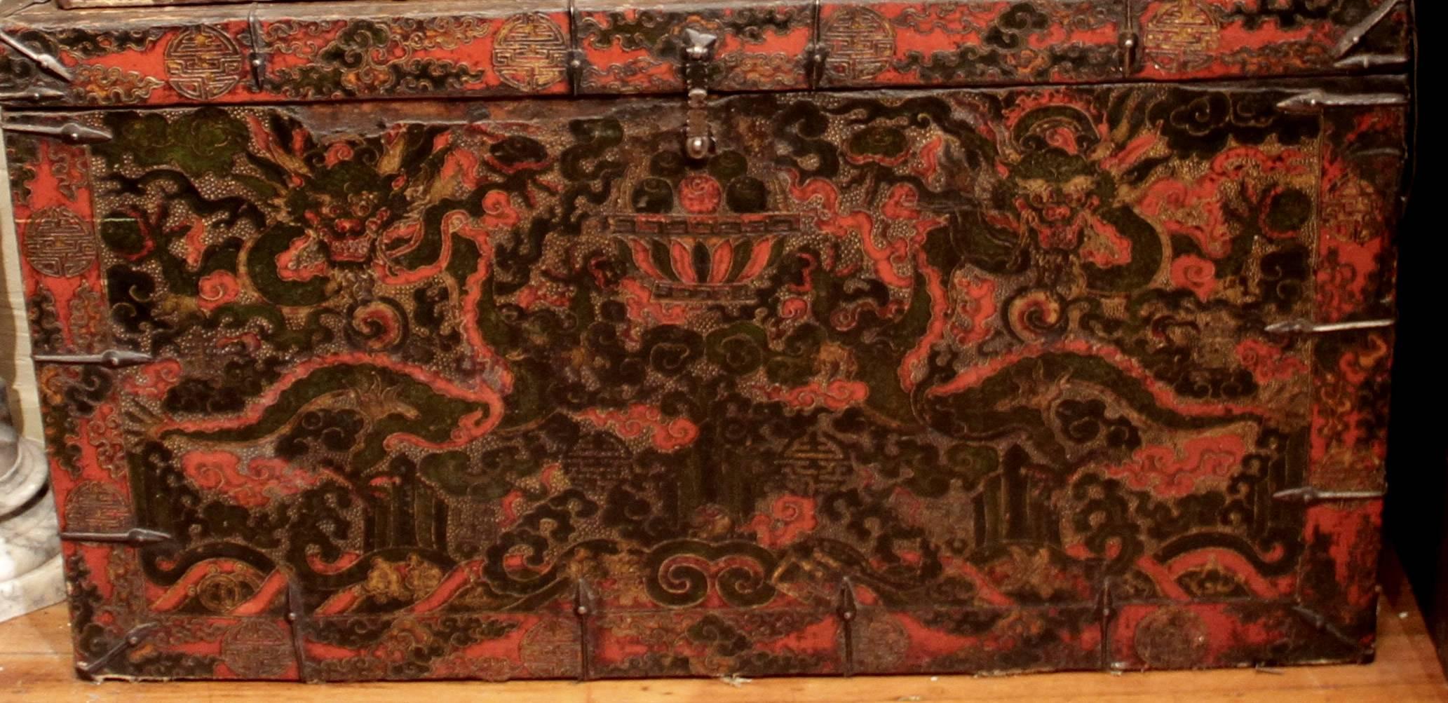 Mythical dragon Tibetan trunk in vibrant used for storing sacred religious objects. It has metal ornamentation and is a Gam Buddhist Monastery Trunk. It has lots of vibrant colors including red and black. Red and black trunks are rare and more