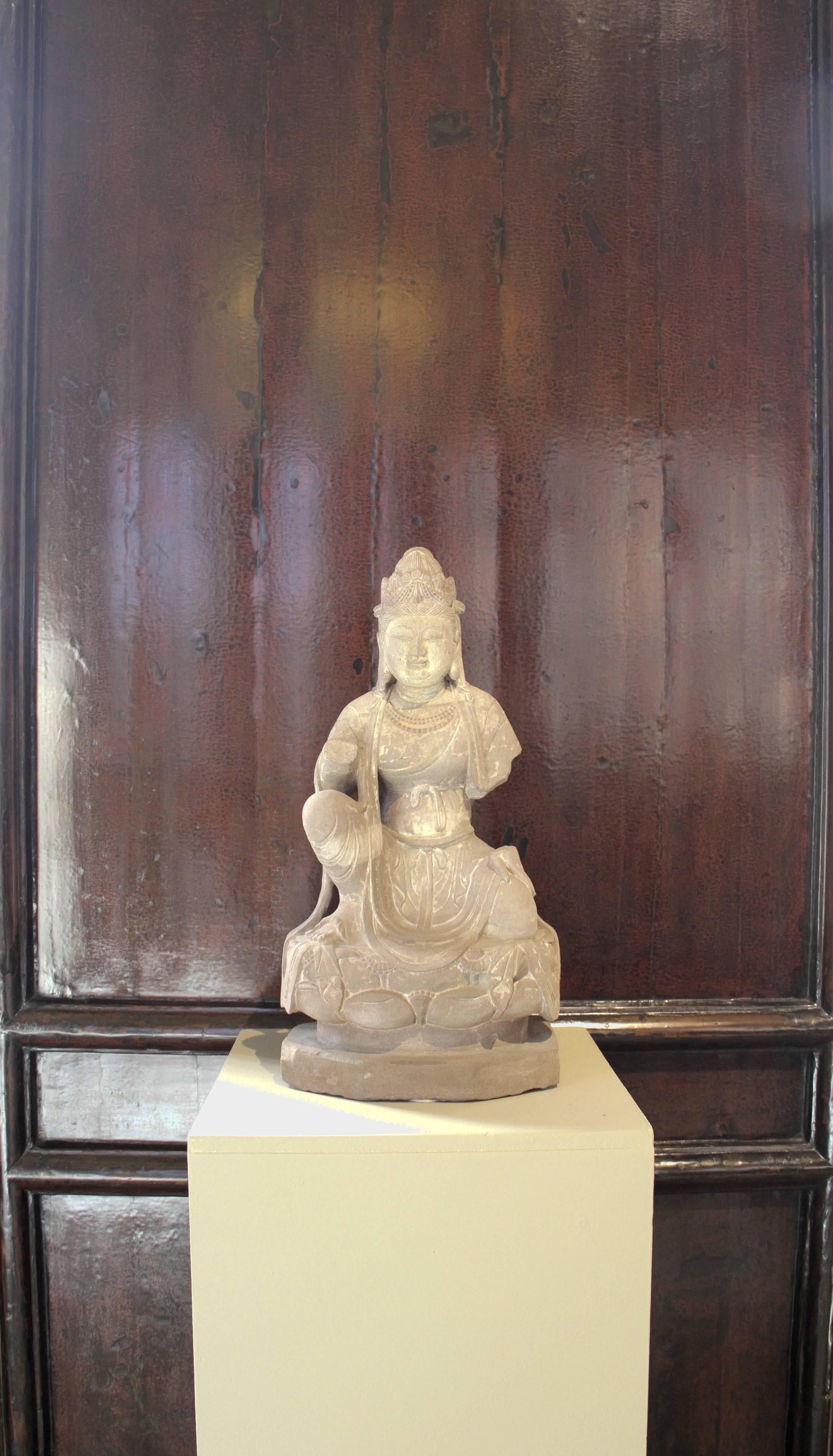 This sandstone Bodhisattva kneeling above a lotus plinth, traces of polychromy is from China, Shanxi province, Tang dynasty and stands 21 inches high. 

In Buddhism, Bodhisattva is the Sanskrit term for anyone who, motivated by great compassion,