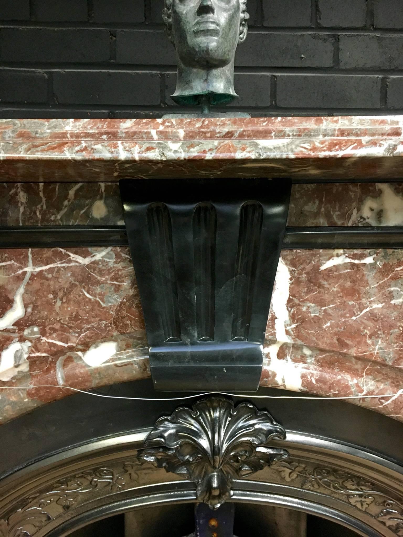 A large and regal antique Victorian arched spandrel fireplace in Deep Red Rosa and Belgian black Marble. A central carved keystone is flanked by two large Arched spandrels with a moulded top above, the whole on top of to capped foot blocks, English,