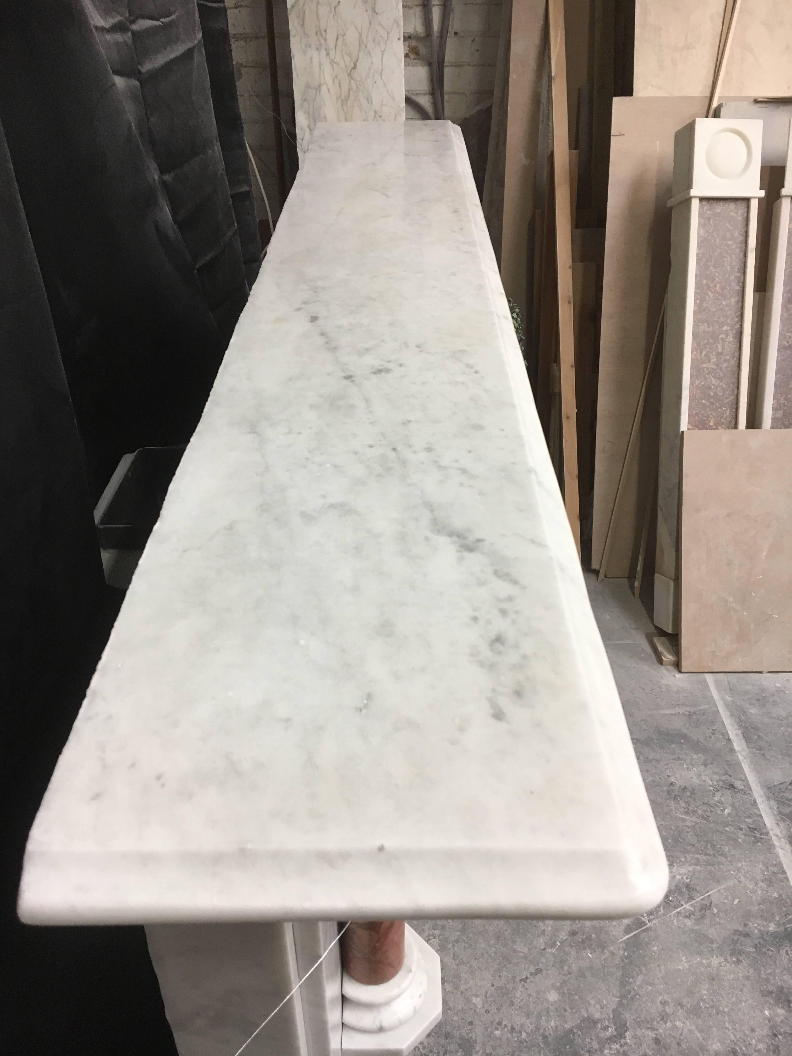 A pleasing and simple Antique Victorian Carrara marble Demi-pillard fireplace, with fluted projected capitols with under mounted Rosso Verona pillars, with Carrara marble capping. Fully restored and polished ready to fit. English, circa
