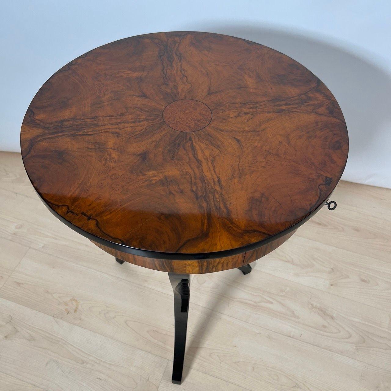 Beautiful round Biedermeier side or sewing table from South Germany 1825.

Walnut veneer on softwood. Round burlwood inlay with ebony edging in the middle of the top. One drawer with interior in maple wood and fold-out pincushion.
Beautiful ebonized