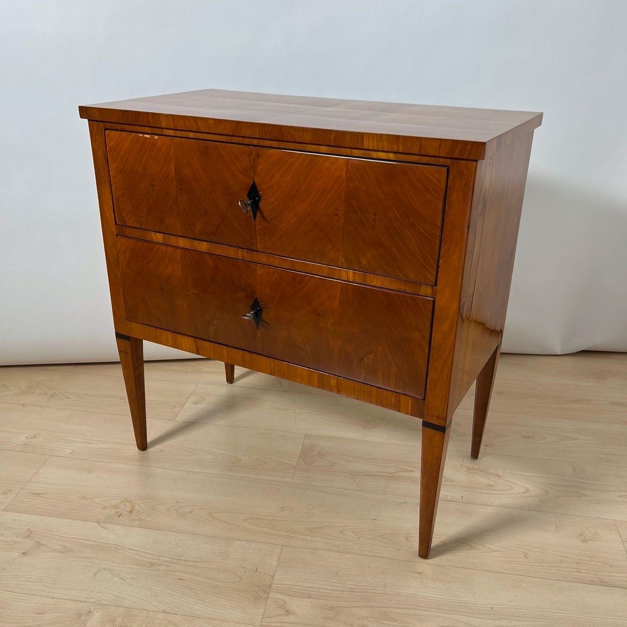 Commode o cassettone Biedermeier di piccole dimensioni e dalla forma lineare, proveniente dalla Germania meridionale, circa 1820.
Ciliegio impiallacciato su legno dolce. Solide gambe coniche quadrate. Diamanti ebanizzati come stemmi chiave. Due