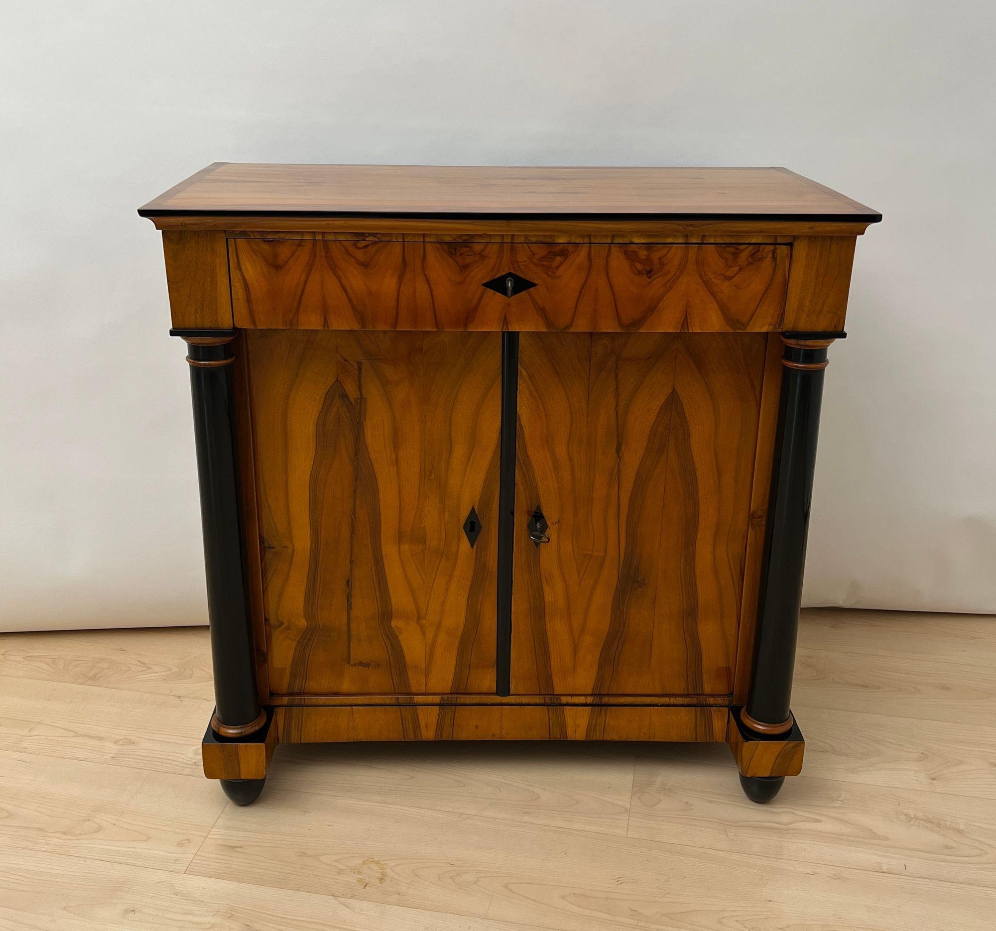 Beautiful, neoclassical Biedermeier Chest or Half-Cabinet in walnut from South Germany around 1825.
Walnut veneered on softwood. Thick, partly ebonized full columns. Ebonized diamonds as key escutcheons.
Below 2 doors counter-veneered in oak on the