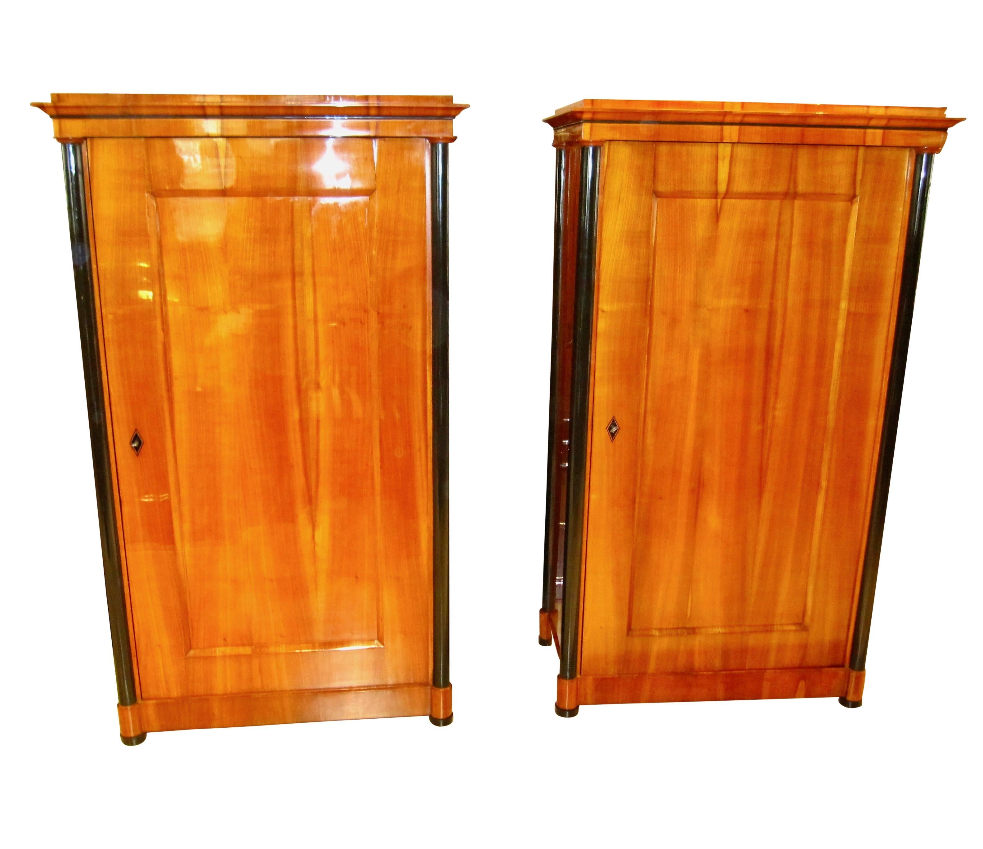 Beautiful and very rare Pair of original Biedermeier armoires/closets from Vienna around 1825. The petite armoires are veneered in a perfect wonderful, bright cherrywood. Each has four ebonized columns, one on every corner. The inside of the doors