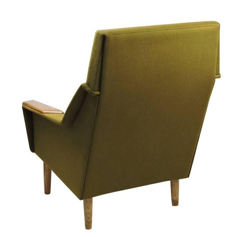 A Danish teak and dark green upholstered armchair standing on four turned tapered legs.