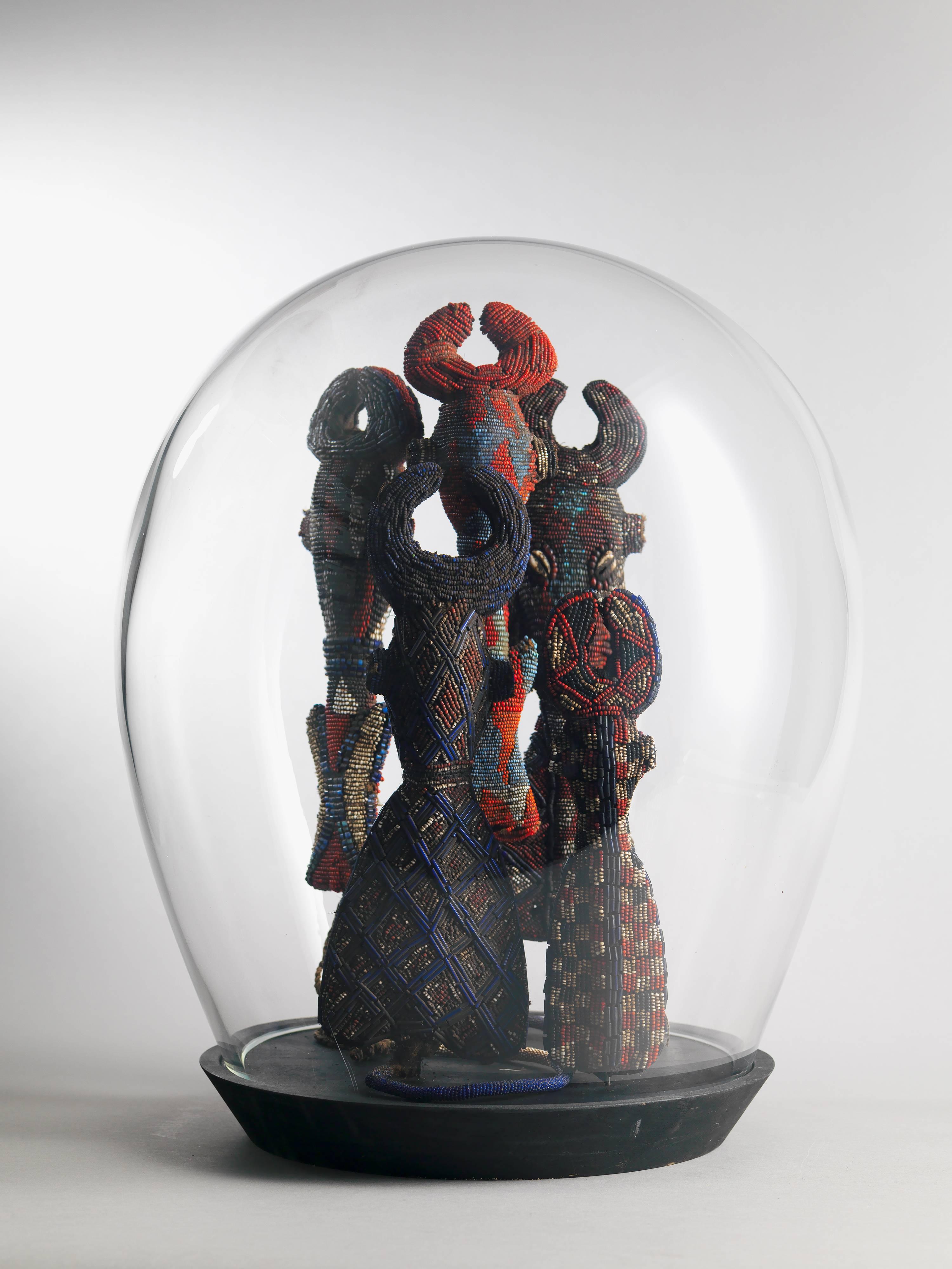 Two very decorative modern handblown domes containing:

Five Ceremonial Flutes or Whistles

Beaded flutes from the Cameroon Grassland come in a variety of geometric form, taking on the shape of a hollowed, stylized figure that combines human and
