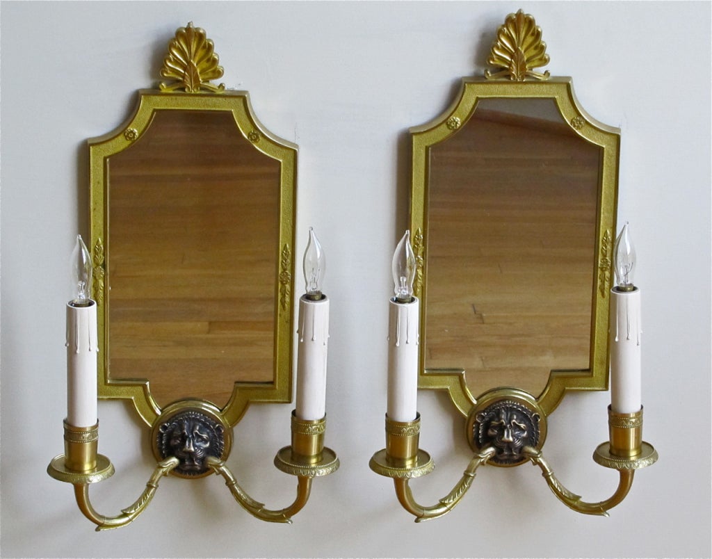Pair of French two-light wall sconces in the French Empire style with ebonized lion motif and inset mirrored backs. High quality casting with crisp chasing. Possibly Maison Charles. Newly wired for US, each sconce uses 2 - B candelabra base bulbs.