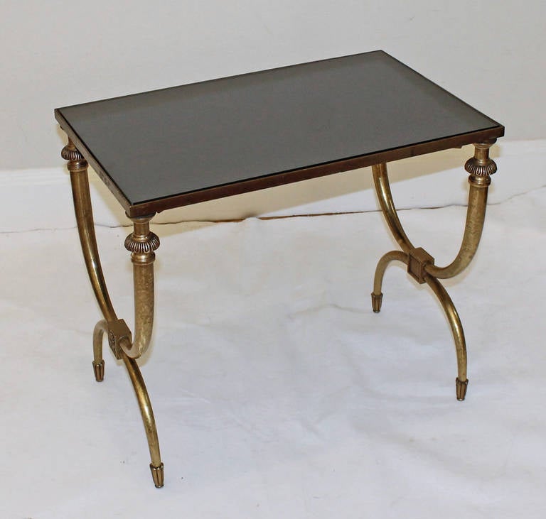 Nicely detailed Curule form brass side or end table with inset dark graphite colored mirrored top. Patina to brass.
  